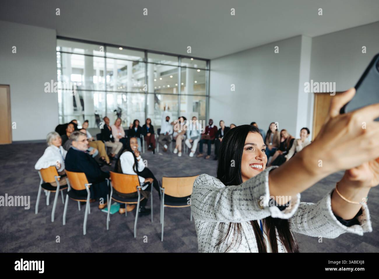 Die Teilnehmer des Firmenworkshops treffen sich zu einem Selfie in Gruppen mit ihrem Kursleiter, um einen Moment der Teamarbeit und Zusammenarbeit in einem modernen Meeting festzuhalten. Stockfoto