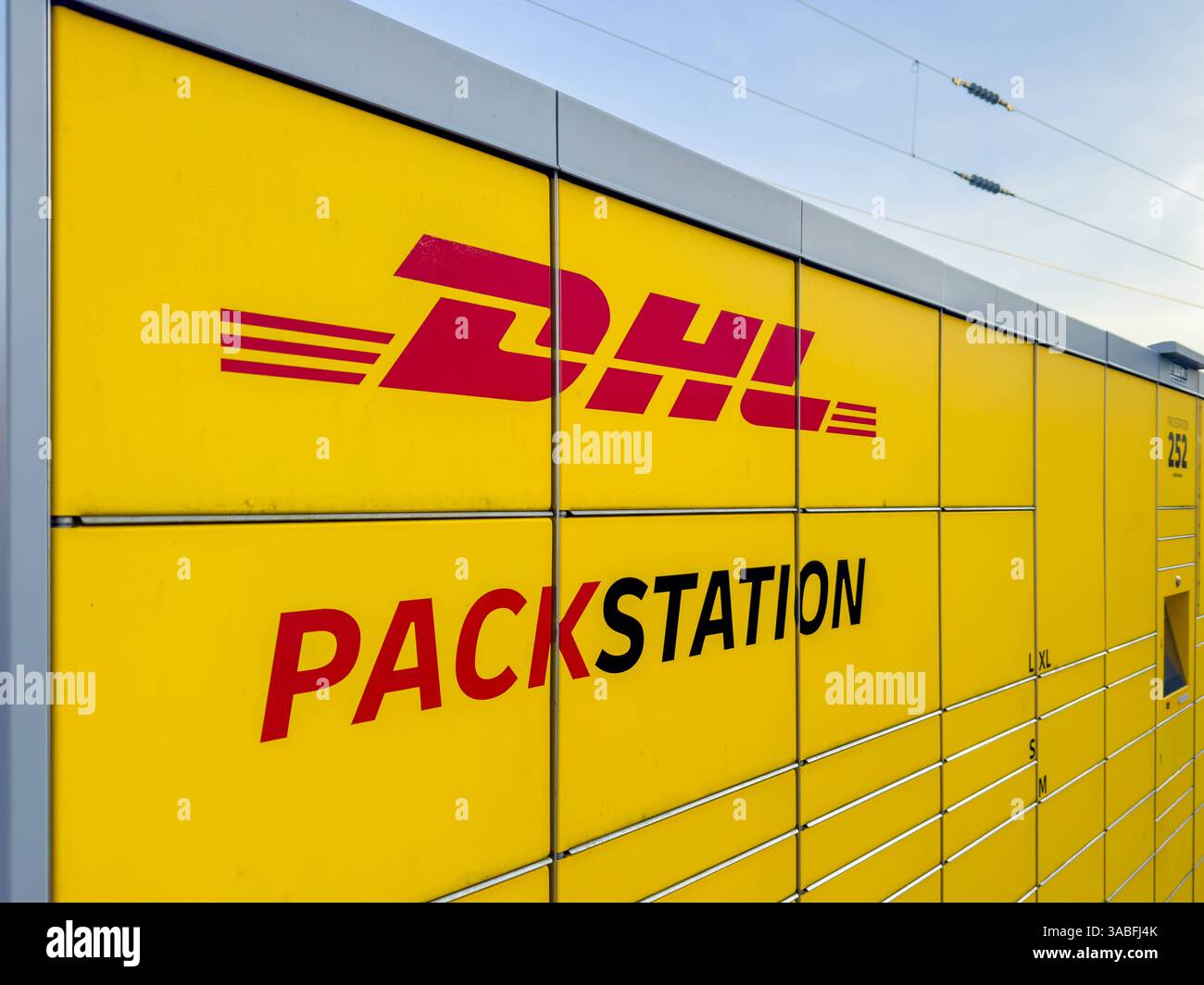 Deutschland, Europa, DHL Packstation, Smart City, Digitalisierung, Logistik, Onlinehandel, E-Commerce, nachhaltige Lieferketten, Paketdienstleister, COâ-Reduktion, Klimaschutzmaßnahmen, urbane Infrastruktur, Fachkräftemangel, Automatisierung, kontaktlose Lieferung, Bahnlogistik, Verkehrswende, Deutsche Bahn, steigende Lebenshaltungskosten, Konsumverhalten, Inflation, soziale Gerechtigkeit, Einzelhandel, Wettbewerbsdruck, Kapitalismuskritik, politische Plakate, EU-Handelspolitik. *** Deutschland, Europa, DHL Packstation, Smart City, Digitalisierung, Logistik, Online-Handel, E-Commerce, nachhaltige Stockfoto