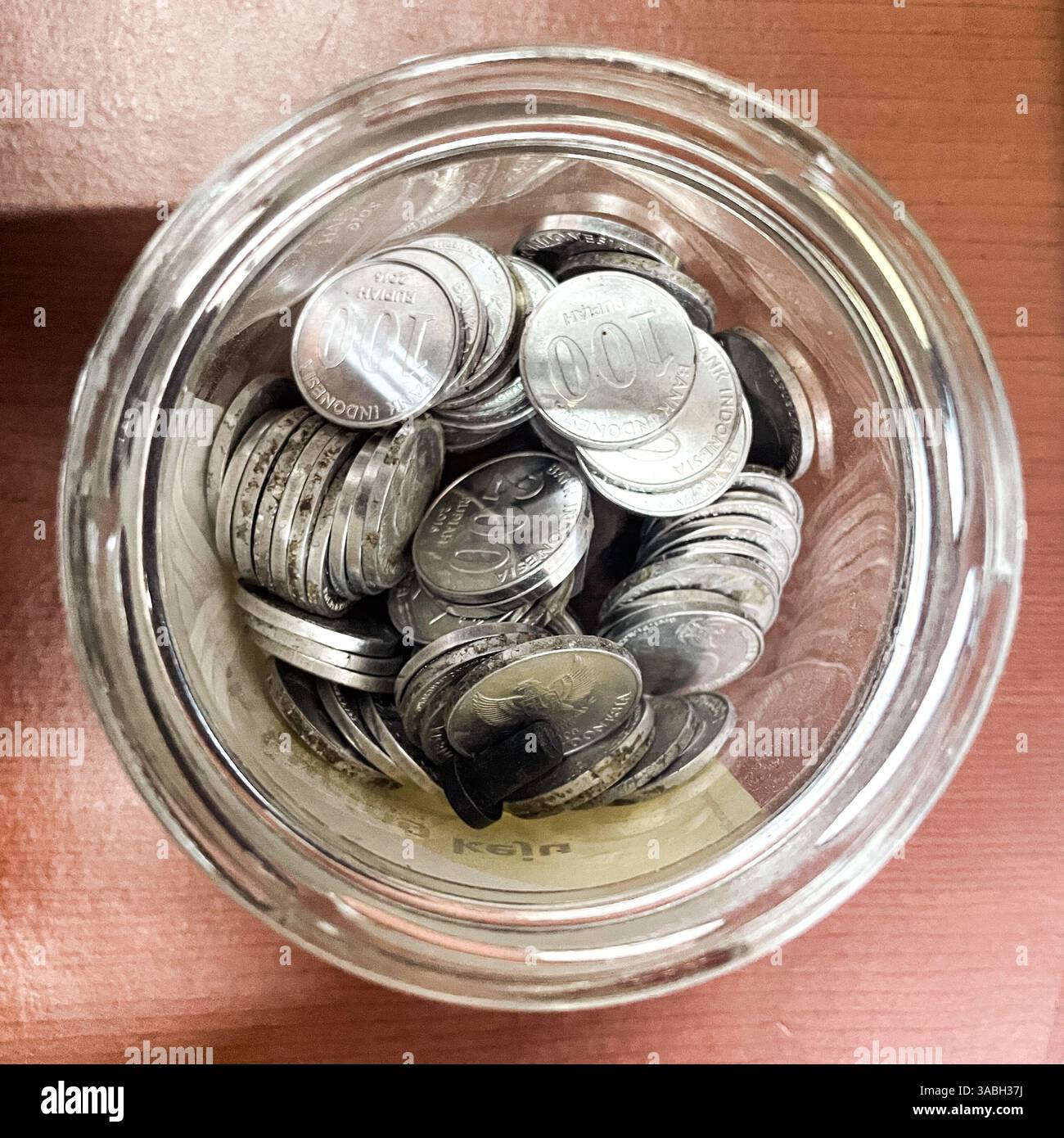 Glas mit Glasspitze von oben mit Rupiah-Münzen - Smartphone-aufgenommenes Stockfoto