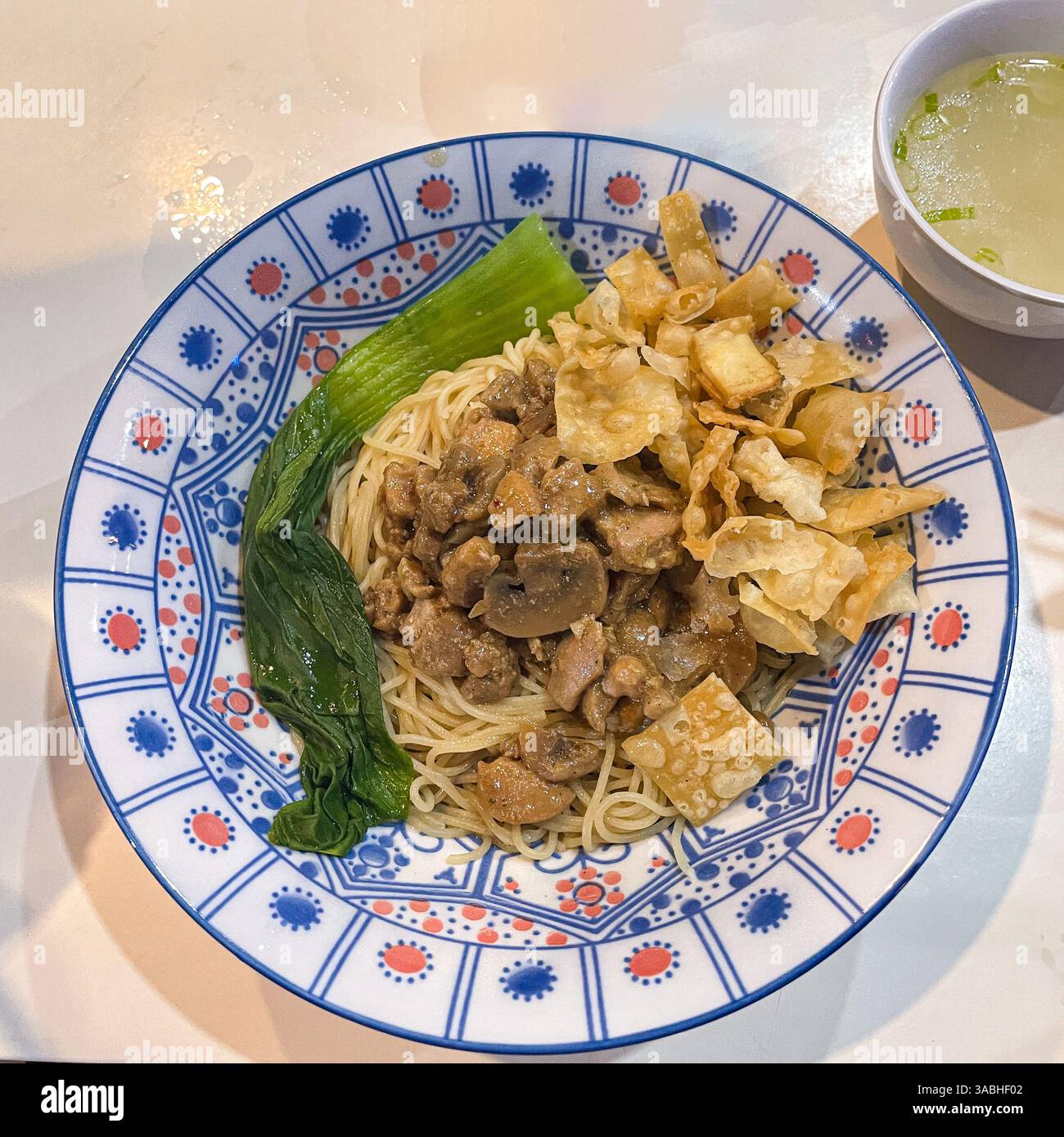 Bakmie , eine Schüssel Nudeln mit Huhn und Pilzen serviert mit separater Brühe - Smartphone-aufgenommenes Stockfoto