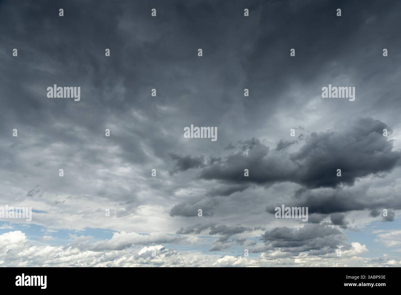 Ein fesselnder Blick auf einen dramatischen bewölkten Himmel mit dunklen Sturmwolken, die teilweise blaue Flecken bedecken. Eine perfekte Darstellung des wechselnden Wetters oder der Stimmung Stockfoto