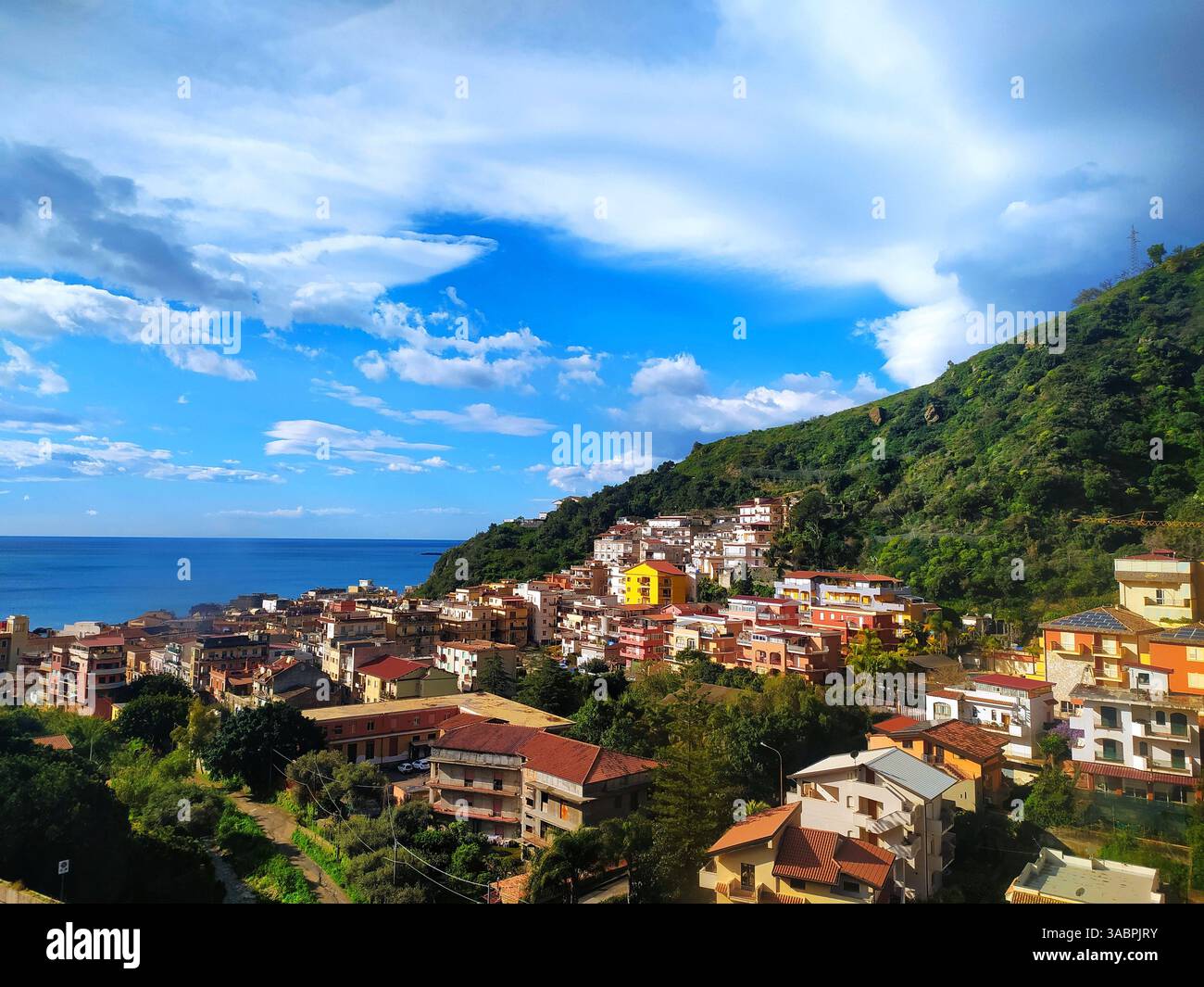 Panoramablick auf Giardini Naxos mit mediterranen Häusern, grünem Hügel und blauem Meer - sizilianisches Touristenziel. Stockfoto