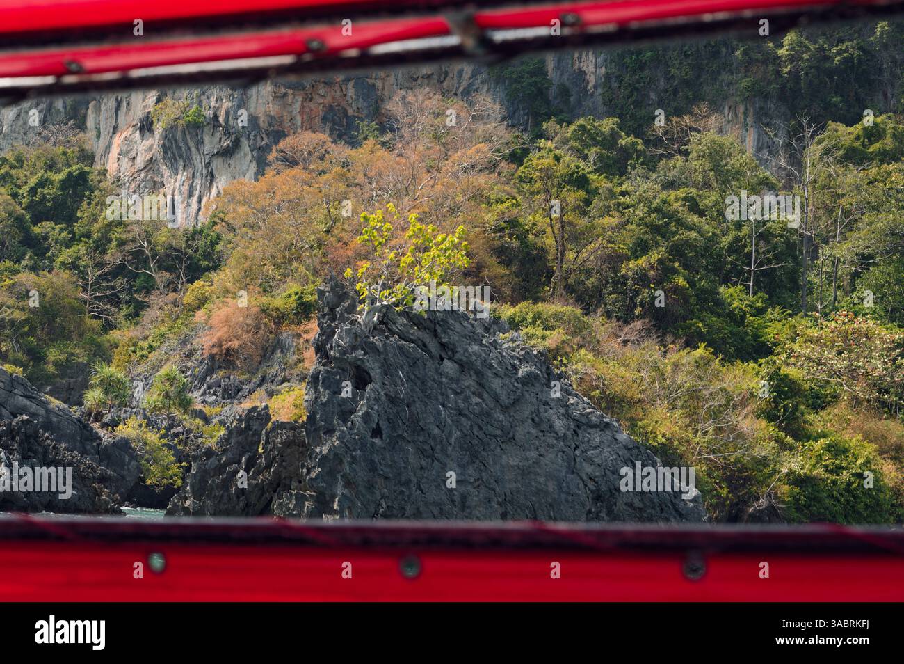 Zerklüftete Klippen und üppiger Dschungel werden durch den Rahmen eines Langboot-Bootes sichtbar Stockfoto