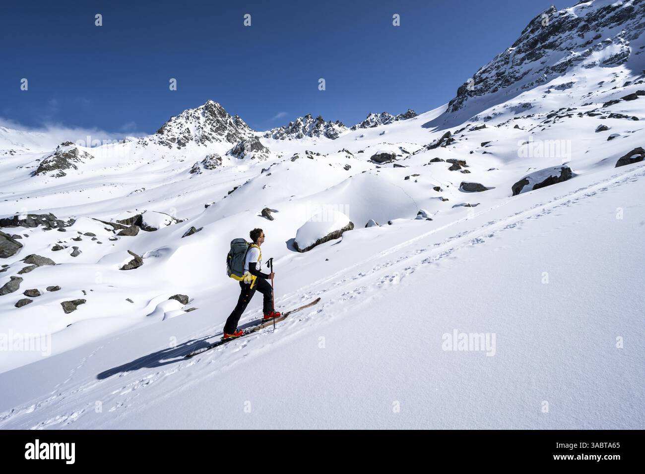 Skitourenfahrer steigen durch eine malerische schneebedeckte Berglandschaft mit Gipfeln hinauf zum Gipfel des Kesch Pitschen, Buendner Haute Route s Stockfoto