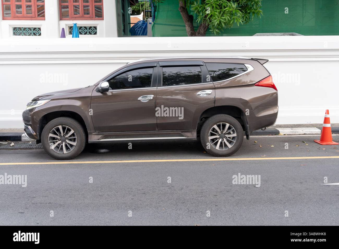 Ein eleganter grauer oder dunkelgrauer SUV-Sportwagen mit Blick auf die linke Seite parkt auf der Stadtstraße in der Nähe des Fußwegs in der Innenstadt. Stockfoto
