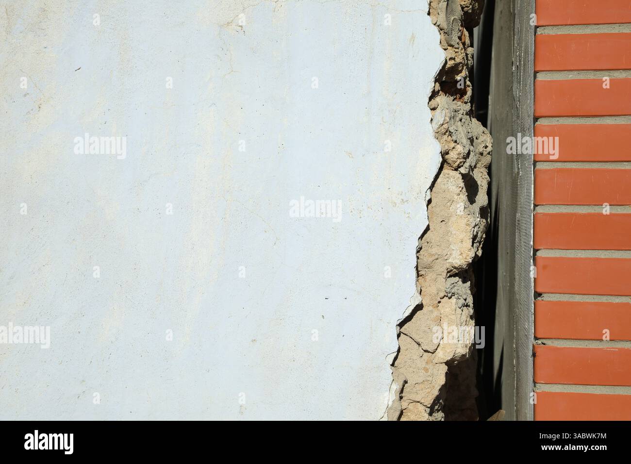 Altes weißes Gebäude in der Nähe einer neuen Backsteinmauer. Erdbeben nach dem Erdbeben Stockfoto