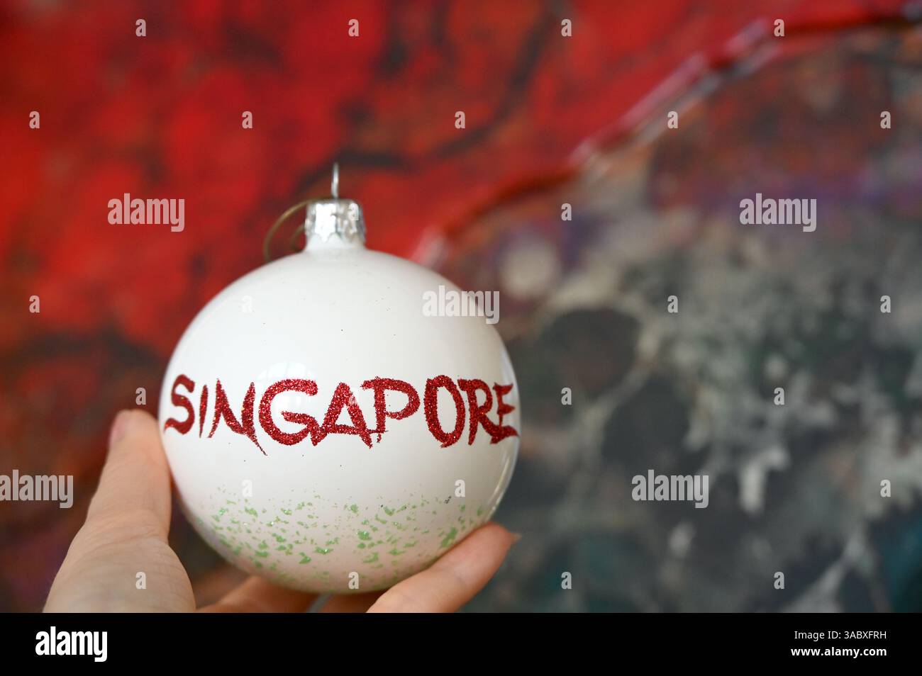 Der Name der Stadt Singapur auf der Dekoration der weißen Kugel in der menschlichen Hand. Stockfoto