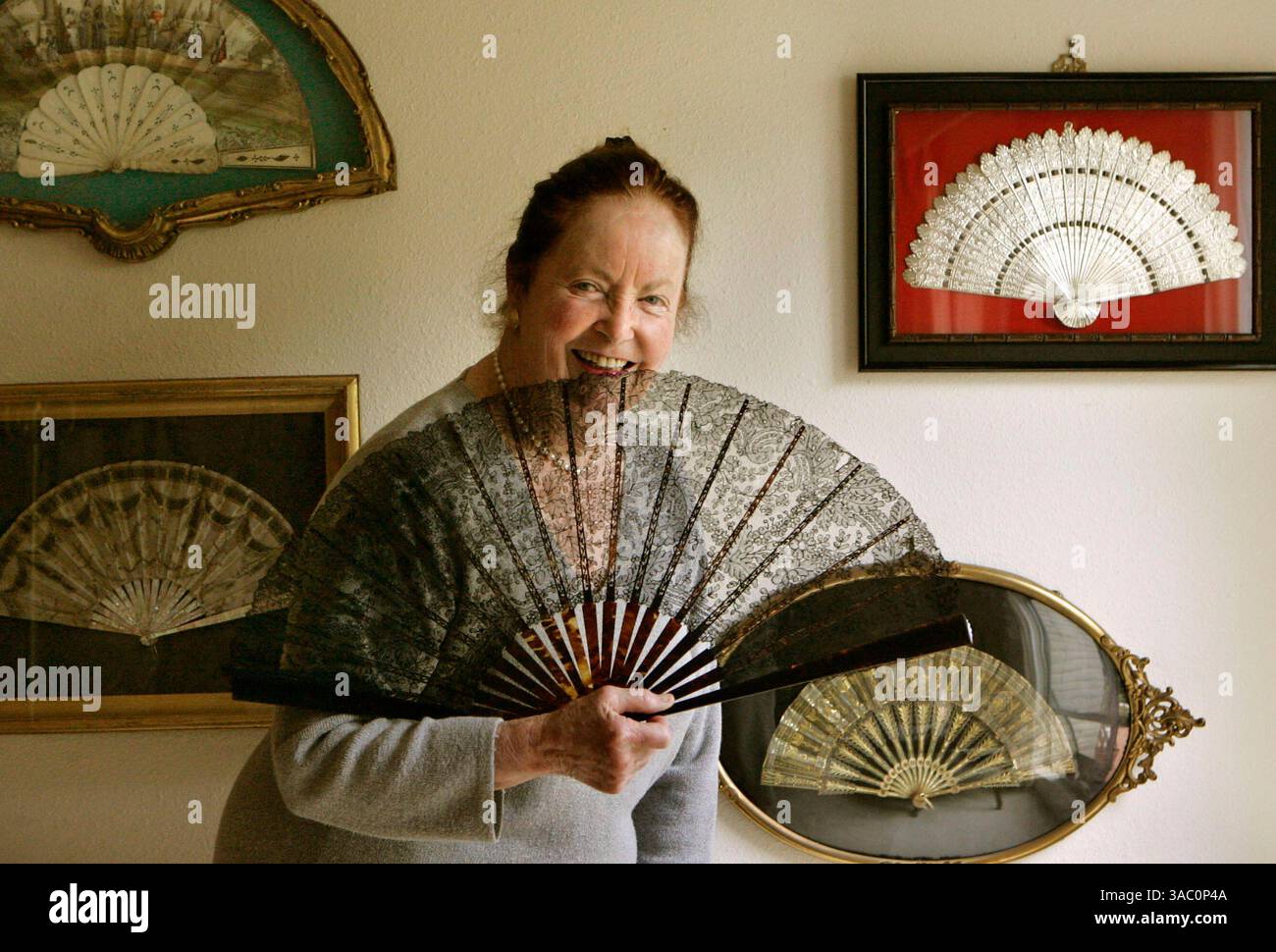 (Veröffentlicht 27.11.2005, E-2) Elin (cq) Parks hielt einen französischen Fan von Chantilly Lace, als sie vor einigen der wertvolleren Fans ihrer Kollektion stand, die an der Wand ihres Hauses La Jolla hing. Stockfoto