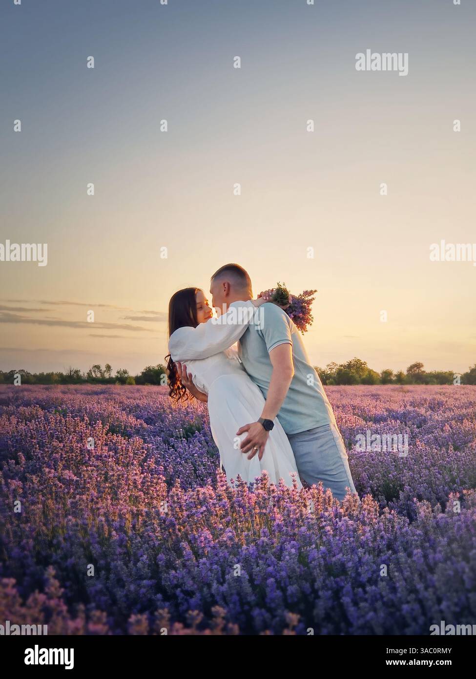 Ein junges Paar tanzt zusammen auf einem Lavendelfeld. Malerische Sommerlandschaft. Liebe und Romantik Hochzeit konzeptuelles Porträt - Smartphone-aufgenommenes Stockfoto