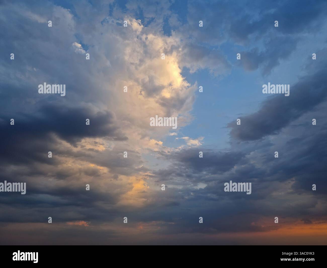 Blick auf den Himmel mit dramatischen Wolken während Sonnenuntergang nach dem Sturm. Das Sonnenlicht blickt hindurch und schafft eine atemberaubende und stimmungsvolle Wolkenlandschaft mit - Smartphone-aufgenommenes Stockfoto