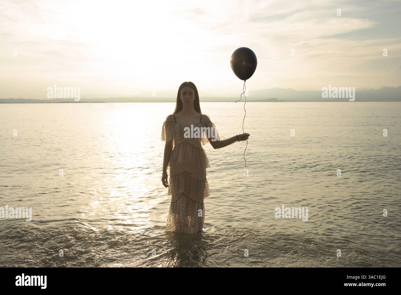 Eine Frau, die einen schwarzen Ballon an der Schnur hält, die entkommen will, ein Konzept der Freiheit Stockfoto