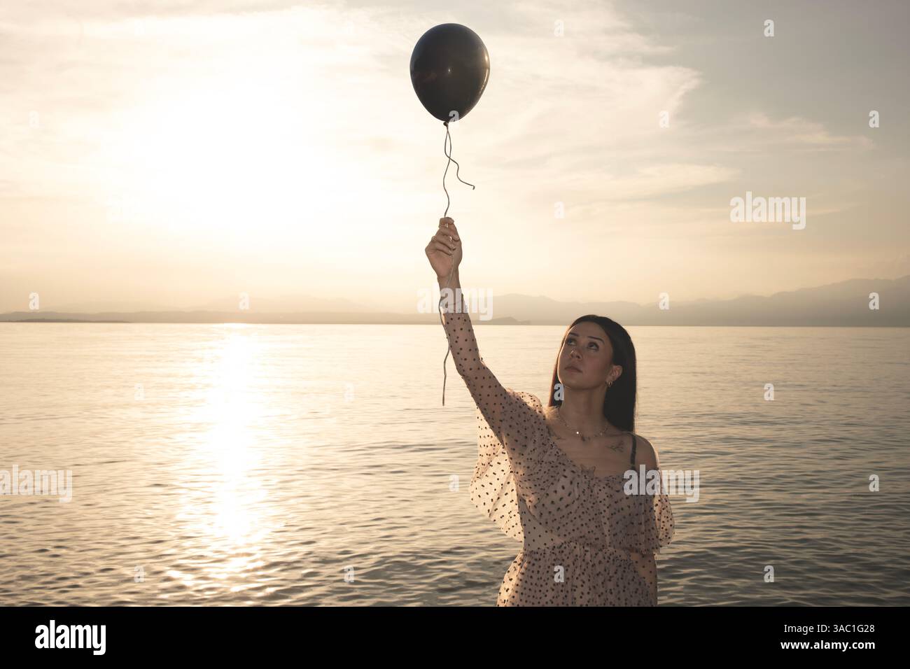 Eine Frau, die einen schwarzen Ballon an der Schnur hält, die entkommen will, ein Konzept der Freiheit Stockfoto