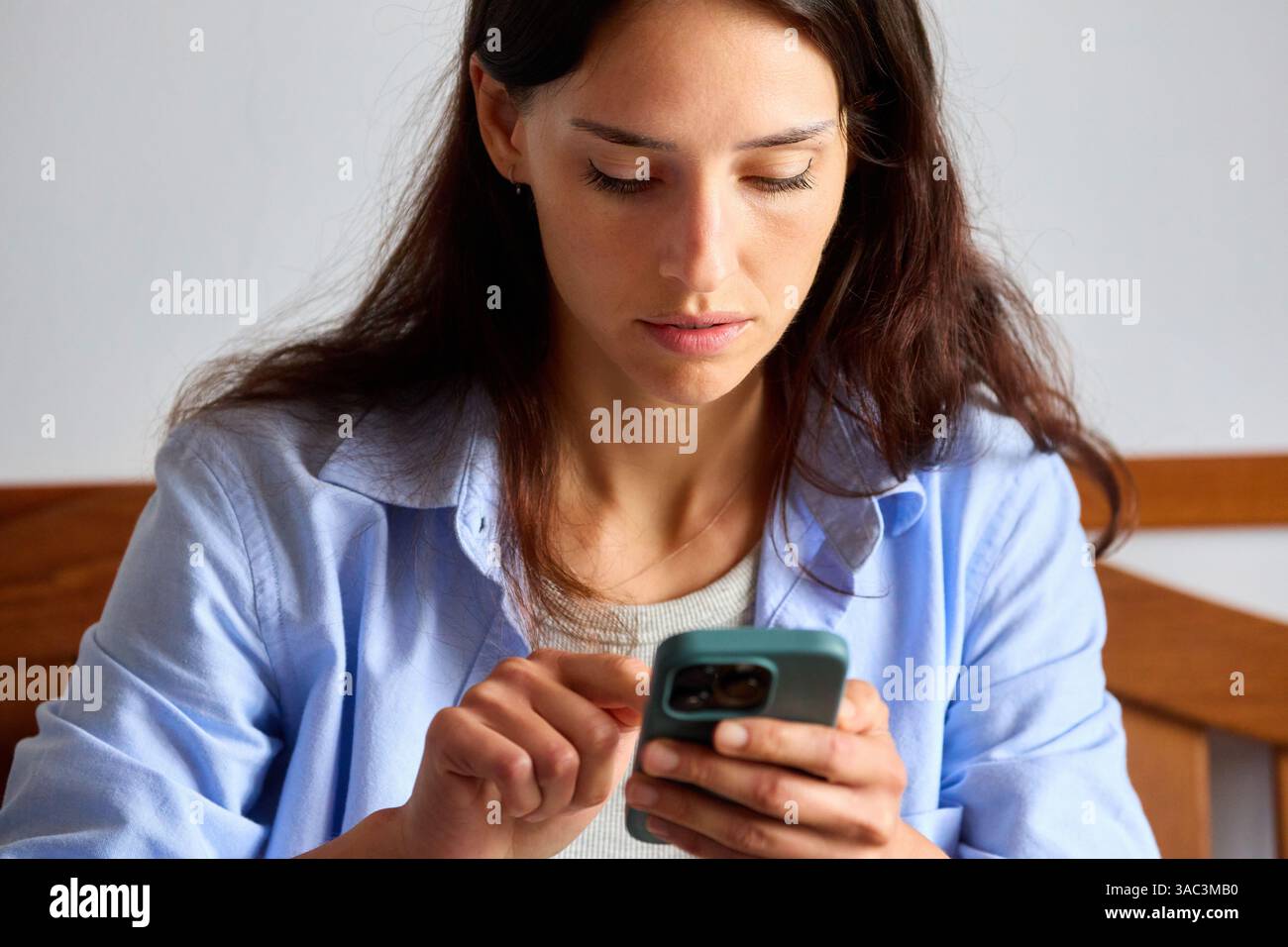 35-jährige Frau, die zu Hause auf das Smartphone schaut Stockfoto