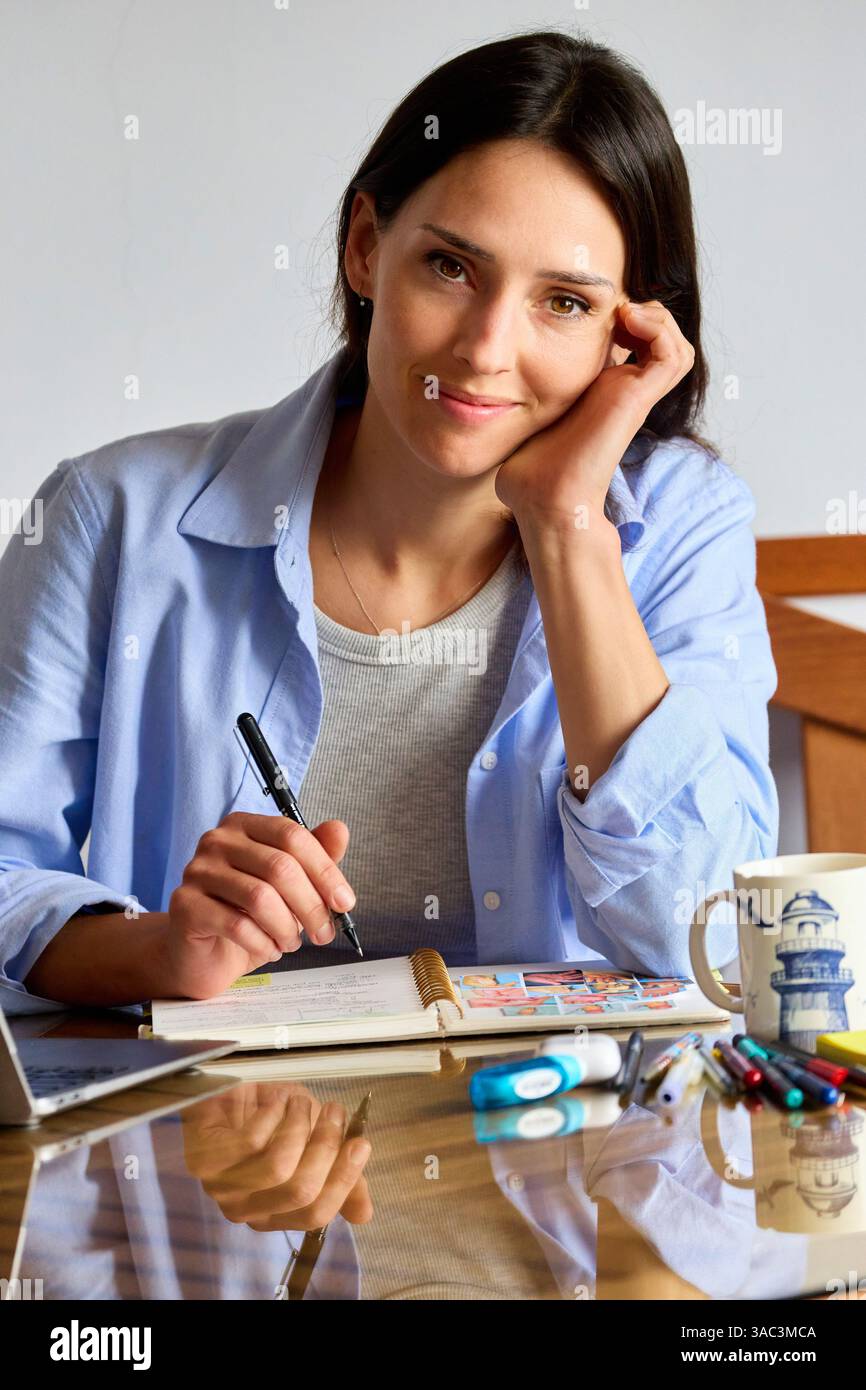 35-jährige Frau, die zu Hause studiert, in die Kamera schaut Stockfoto