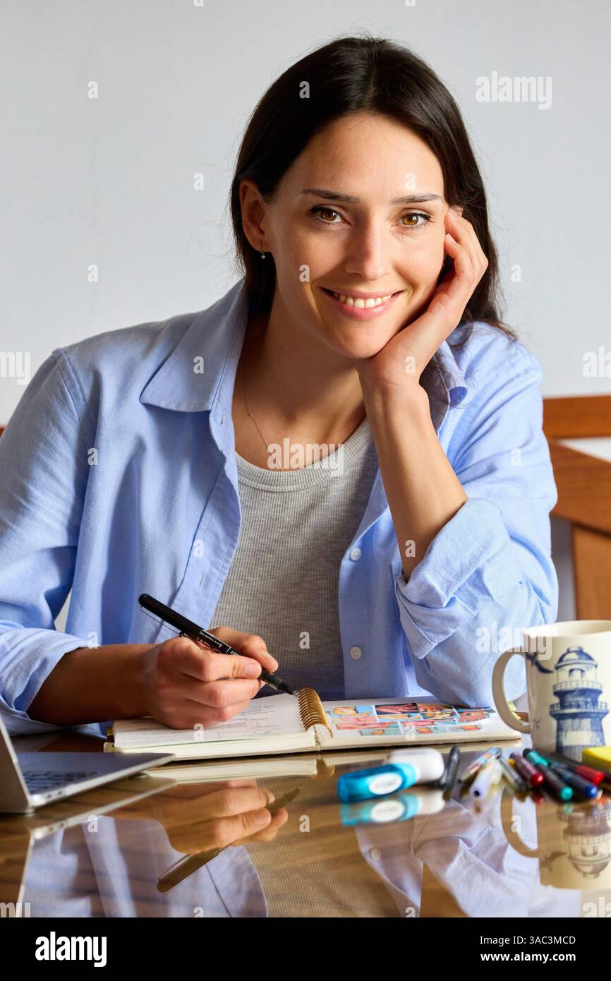 35-jährige Frau, die zu Hause studiert, in die Kamera schaut Stockfoto