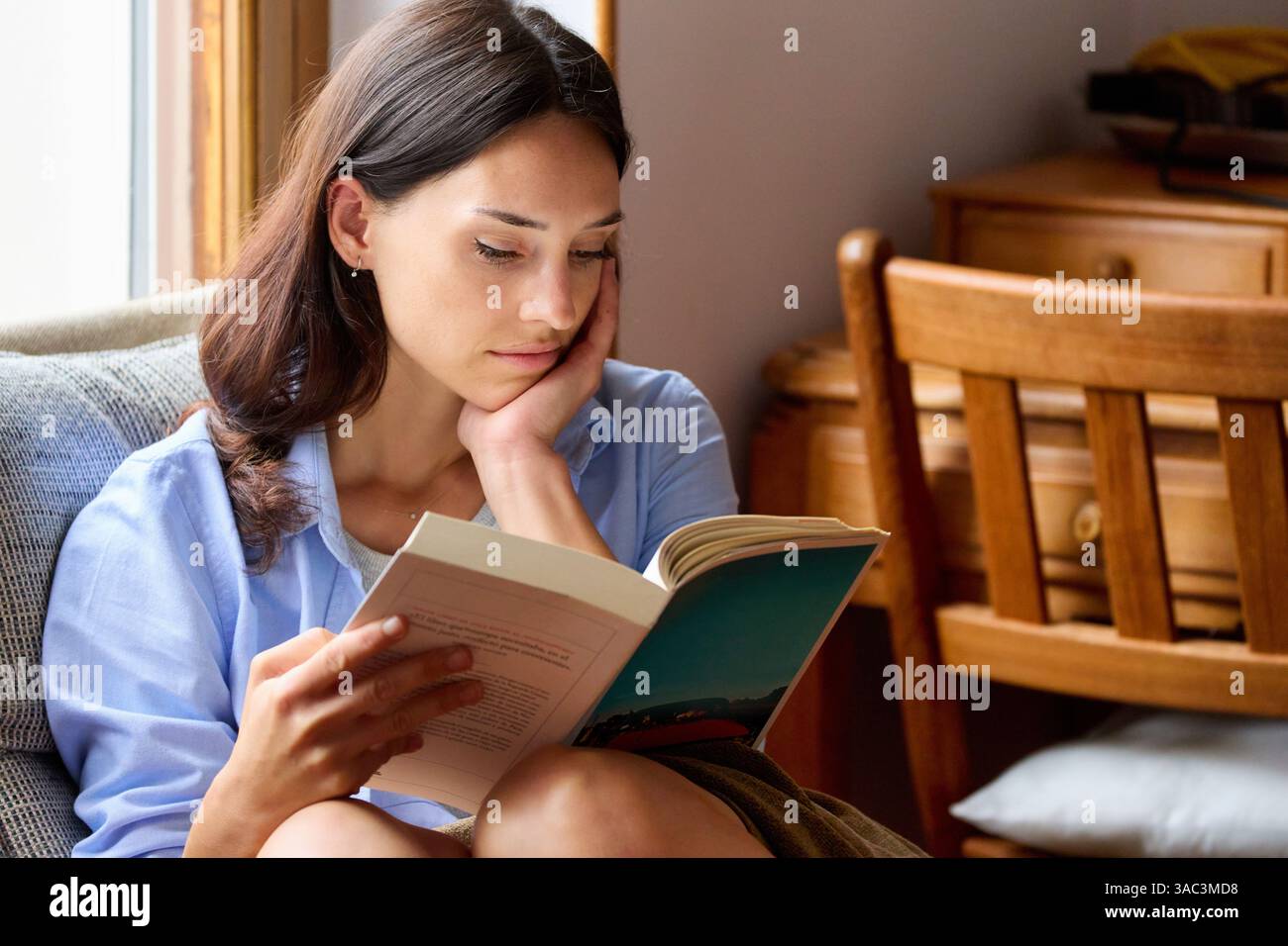35-jährige Frau zu Hause, liest ein Buch Stockfoto