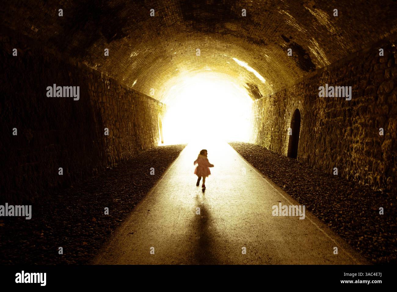 Kleines Kind, das am Ende des Tunnels auf das Licht zuläuft Stockfoto