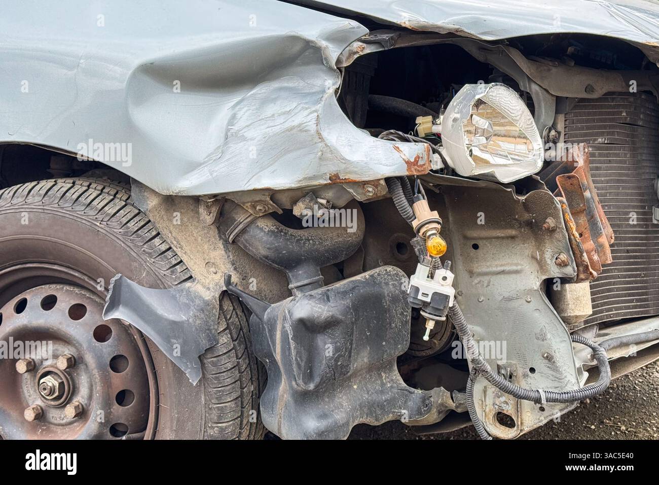 Eine Nahaufnahme eines beschädigten Fahrzeugs zeigt einen zerknitterten Kotflügel, freiliegende Scheinwerferkomponenten und verbogenes Metall nach einer Kollision Stockfoto