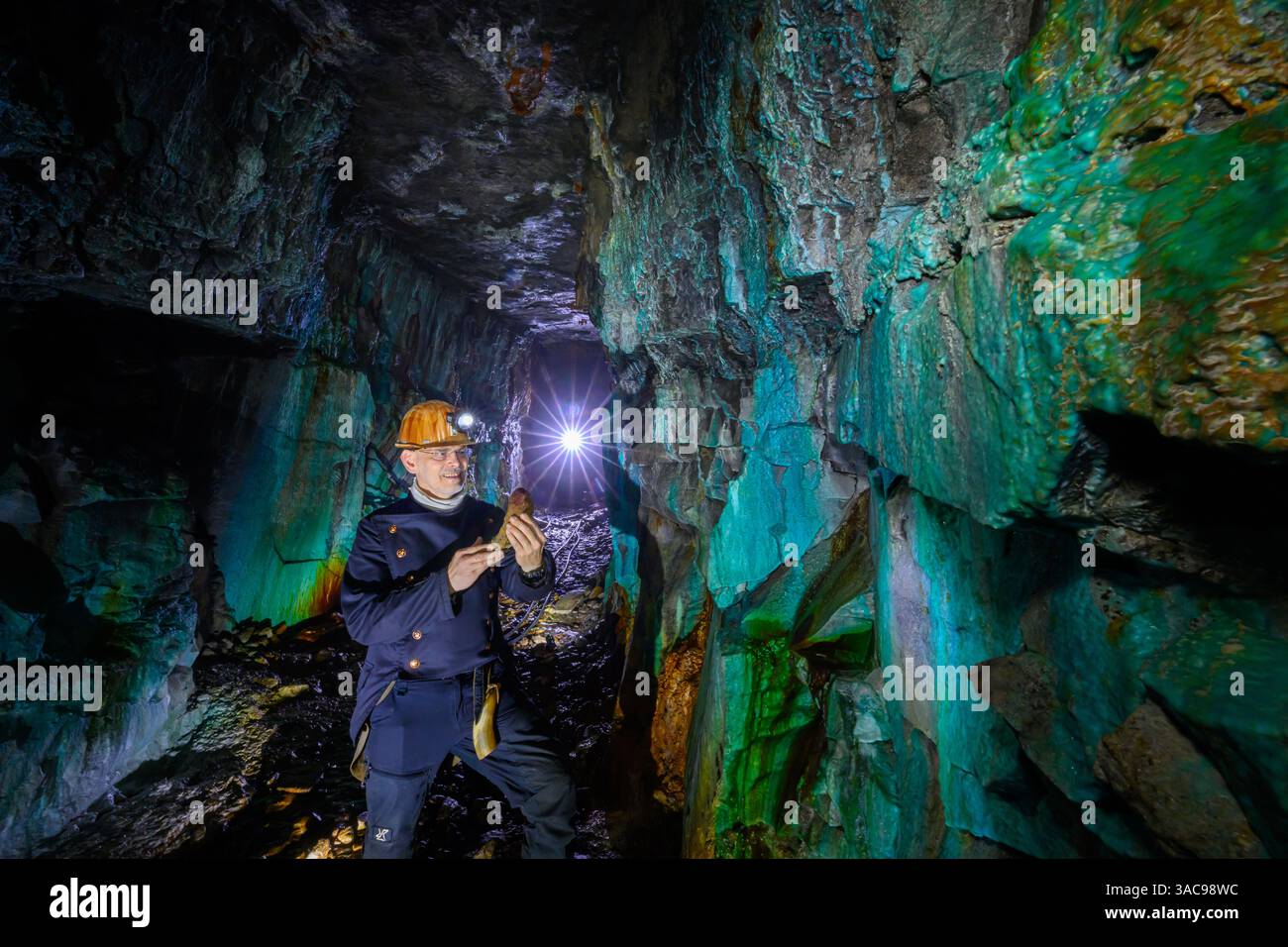 PRODUKTION - 02. April 2025, Sachsen-Anhalt, Sangerhausen: Thomas Wäsche, Leiter des Erlebniszentrums Bergbau Röhrigschacht Wettelrode, steht fast 300 Meter unterirdisch im sogenannten Grünen Gewölbe. Das Sintern wird durch gelöste Mineralien aus dem Kalkstein verursacht. Die Farbpalette reicht von kräftigen Brauntönen bis zu weiß, Grün, Türkis, Blau und Schwarz. Die ersten Bergleute begannen vor 825 Jahren in der Region Mansfeld mit dem Graben nach Kupfererz. Ab 1750 wurde ein intensiver Bergbau durchgeführt. Insgesamt wurden rund 2,6 Millionen Tonnen Kupfer und 14.213 Tonnen Silber aus dem Erz gewonnen Stockfoto