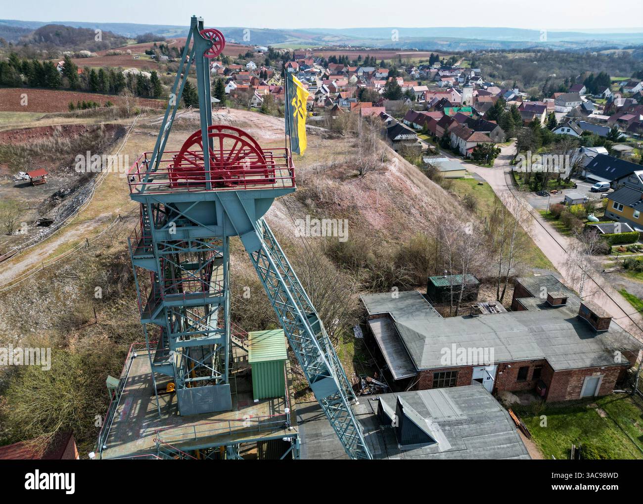 PRODUKTION - 02. April 2025, Sachsen-Anhalt, Sangerhausen: Der gewundene Turm erhebt sich auffallend über dem Erlebniszentrum Bergbau Röhrigschacht Wettelrode. (Foto mit Drohne) die ersten Bergleute begannen vor 825 Jahren in der Region Mansfeld nach Kupfererz zu graben. Ab 1750 wurde ein intensiver Bergbau durchgeführt. Insgesamt wurden rund 2,6 Millionen Tonnen Kupfer und 14.213 Tonnen Silber aus dem Erz in der Region gewonnen. Bis Dezember werden insgesamt 38 Veranstaltungen an den Beginn der Bergbau- und Hüttenwirtschaft in der Region Mansfeld erinnern. Als bedeutender Kupfer- und Silberproduzent ist die Region Contra Stockfoto