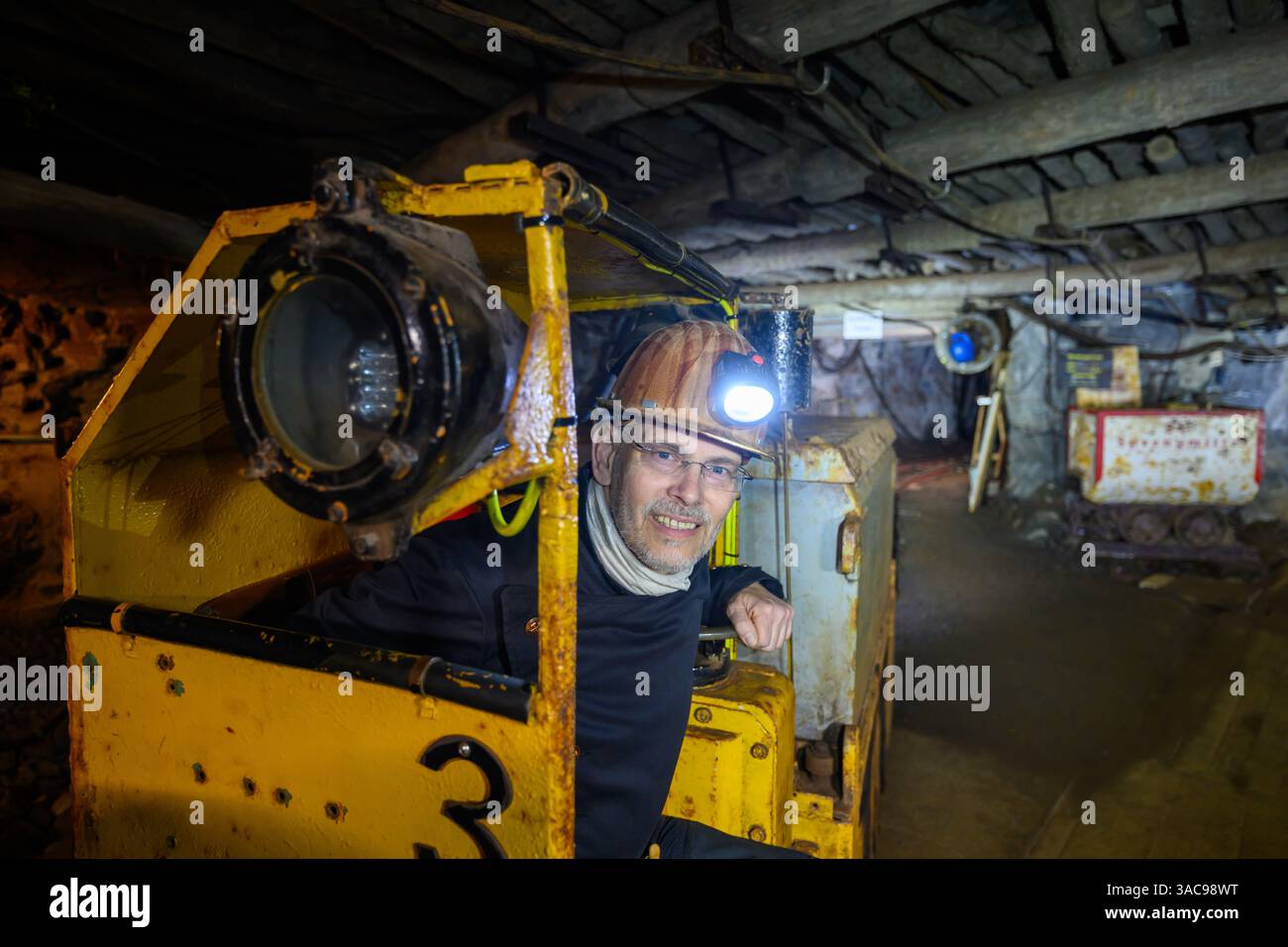 PRODUKTION - 02. April 2025, Sachsen-Anhalt, Sangerhausen: In fast 300 Metern Tiefe sitzt Thomas Wäsche, Leiter des Erlebniszentrums Bergbau Röhrigschacht Wettelrode, unterirdisch in der Grubenlokomotive. Die ersten Bergleute begannen vor 825 Jahren in der Region Mansfeld mit dem Graben nach Kupfererz. Ab 1750 wurde ein intensiver Bergbau durchgeführt. Insgesamt wurden rund 2,6 Millionen Tonnen Kupfer und 14.213 Tonnen Silber aus dem Erz in der Region gewonnen. Bis Dezember werden insgesamt 38 Veranstaltungen an den Beginn der Bergbau- und Hüttenwirtschaft in der Region Mansfeld erinnern. Als bedeutender Kupfer- und Silberproduzent Stockfoto