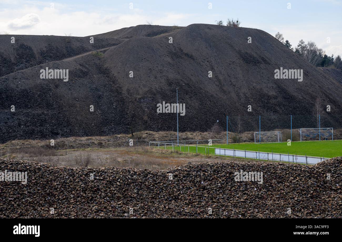 PRODUKTION - 02. April 2025, Sachsen-Anhalt, Kreisfeld: Zwischen Bergschlackenhaufen liegt ein Fußballfeld in Kreisfeld. Das Bergbaugebiet des Mansfeld ist durch die typischen Schlackenhaufen gekennzeichnet. Die ersten Bergleute begannen vor 825 Jahren in der Region Mansfeld mit dem Graben nach Kupfererz. Ab 1750 wurde ein intensiver Bergbau durchgeführt. Insgesamt wurden rund 2,6 Millionen Tonnen Kupfer und 14.213 Tonnen Silber aus dem Erz in der Region gewonnen. Bis Dezember werden insgesamt 38 Veranstaltungen an den Beginn der Bergbau- und Hüttenwirtschaft in der Region Mansfeld erinnern. Als bedeutender Kupfer- und Silberproduzent Stockfoto