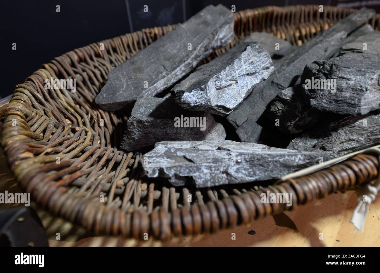 PRODUKTION - 02. April 2025, Sachsen-Anhalt, Sangerhausen: Kupferschiefer liegt in einem historischen Korb in der Ausstellung im Erlebniszentrum Bergbau Röhrigschacht Wettelrode. Die ersten Bergleute begannen vor 825 Jahren in der Region Mansfeld mit dem Graben nach Kupfererz. Ab 1750 wurde ein intensiver Bergbau durchgeführt. Insgesamt wurden rund 2,6 Millionen Tonnen Kupfer und 14.213 Tonnen Silber aus dem Erz in der Region gewonnen. Bis Dezember werden insgesamt 38 Veranstaltungen an den Beginn der Bergbau- und Hüttenwirtschaft in der Region Mansfeld erinnern. Als bedeutender Kupfer- und Silberproduzent trug die Region dazu bei Stockfoto