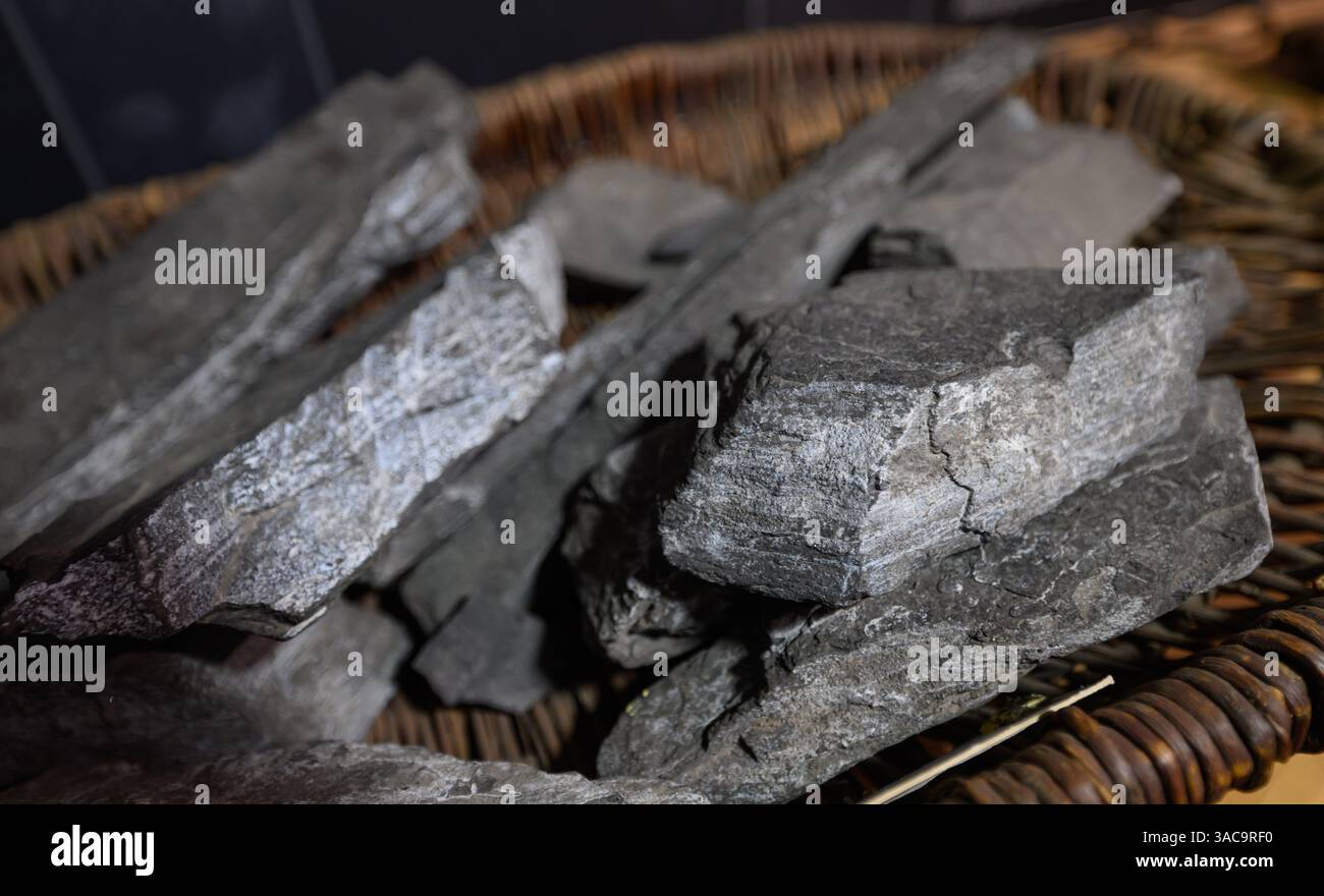 PRODUKTION - 02. April 2025, Sachsen-Anhalt, Sangerhausen: Kupferschiefer liegt in einem historischen Korb in der Ausstellung im Erlebniszentrum Bergbau Röhrigschacht Wettelrode. Die ersten Bergleute begannen vor 825 Jahren in der Region Mansfeld mit dem Graben nach Kupfererz. Ab 1750 wurde ein intensiver Bergbau durchgeführt. Insgesamt wurden rund 2,6 Millionen Tonnen Kupfer und 14.213 Tonnen Silber aus dem Erz in der Region gewonnen. Bis Dezember werden insgesamt 38 Veranstaltungen an den Beginn der Bergbau- und Hüttenwirtschaft in der Region Mansfeld erinnern. Als bedeutender Kupfer- und Silberproduzent trug die Region dazu bei Stockfoto