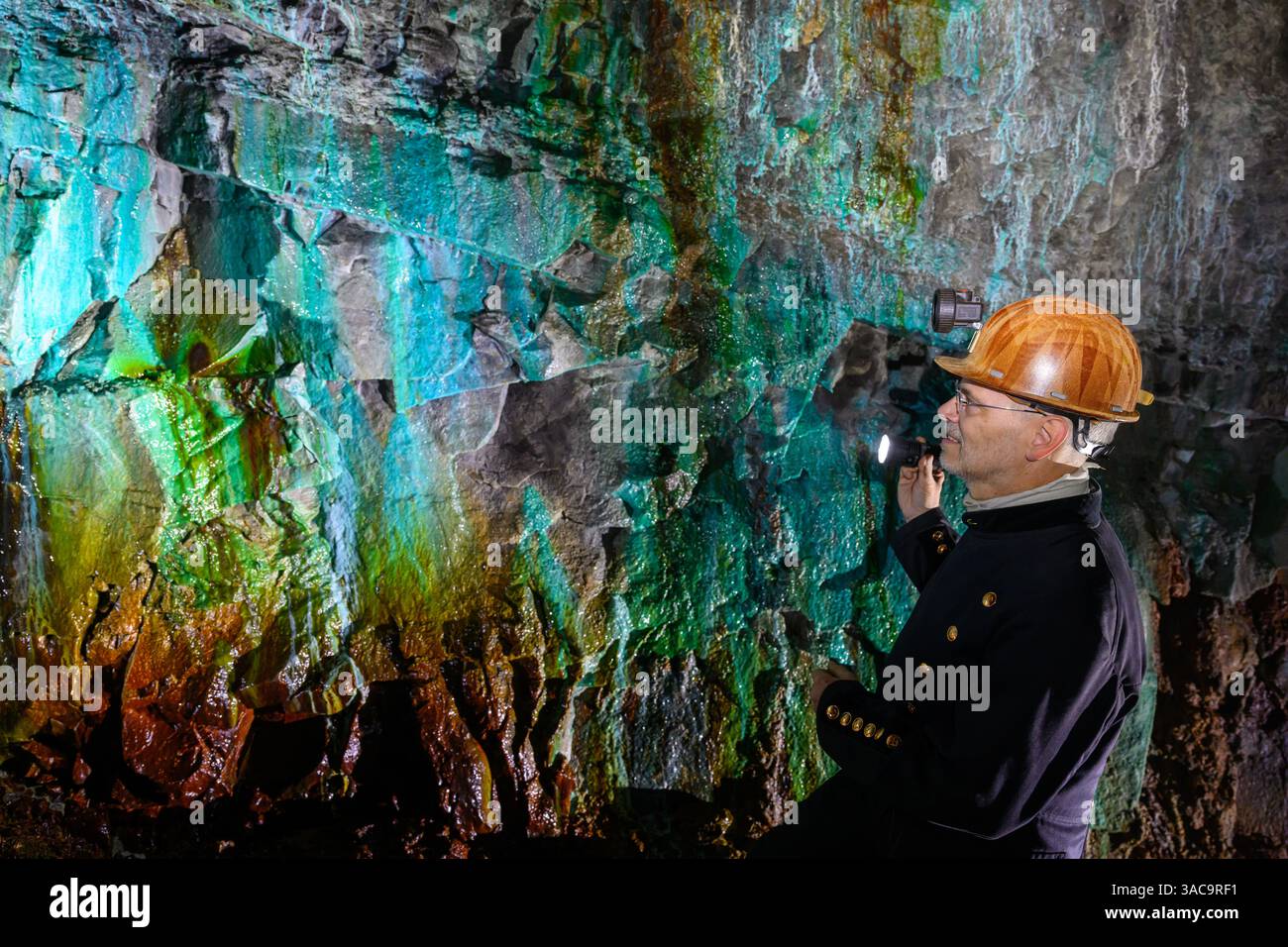PRODUKTION - 02. April 2025, Sachsen-Anhalt, Sangerhausen: Thomas Wäsche, Leiter des Erlebniszentrums Bergbau Röhrigschacht Wettelrode, steht fast 300 Meter unterirdisch im sogenannten Grünen Gewölbe. Das Sintern wird durch gelöste Mineralien aus dem Kalkstein verursacht. Die Farbpalette reicht von kräftigen Brauntönen bis zu weiß, Grün, Türkis, Blau und Schwarz. Die ersten Bergleute begannen vor 825 Jahren in der Region Mansfeld mit dem Graben nach Kupfererz. Ab 1750 wurde ein intensiver Bergbau durchgeführt. Insgesamt wurden rund 2,6 Millionen Tonnen Kupfer und 14.213 Tonnen Silber aus dem Erz gewonnen Stockfoto