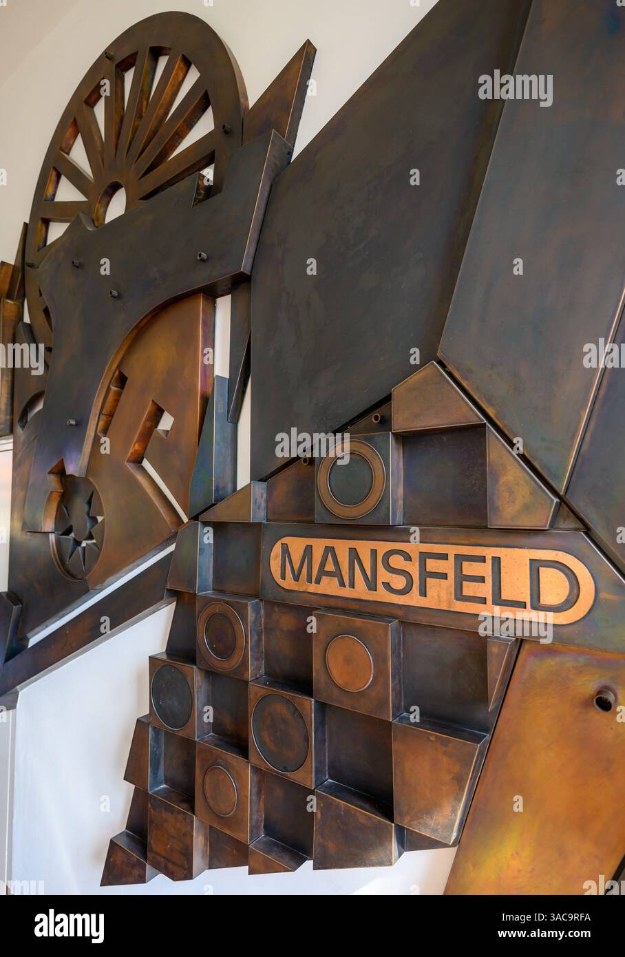 PRODUKTION - 02. April 2025, Sachsen-Anhalt, Hettstedt: Im Mansfeld Museum in Hettstedt ist ein Wandrelief mit der Schrift des Mansfeld-Kombiniers zu sehen. Die ersten Bergleute begannen vor 825 Jahren in der Region Mansfeld mit dem Graben nach Kupfererz. Ab 1750 wurde ein intensiver Bergbau durchgeführt. Insgesamt wurden rund 2,6 Millionen Tonnen Kupfer und 14.213 Tonnen Silber aus dem Erz in der Region gewonnen. Bis Dezember werden insgesamt 38 Veranstaltungen an den Beginn der Bergbau- und Hüttenwirtschaft in der Region Mansfeld erinnern. Als bedeutender Kupfer- und Silberproduzent trug die Region zur wirtschaftlichen Entwicklung bei Stockfoto