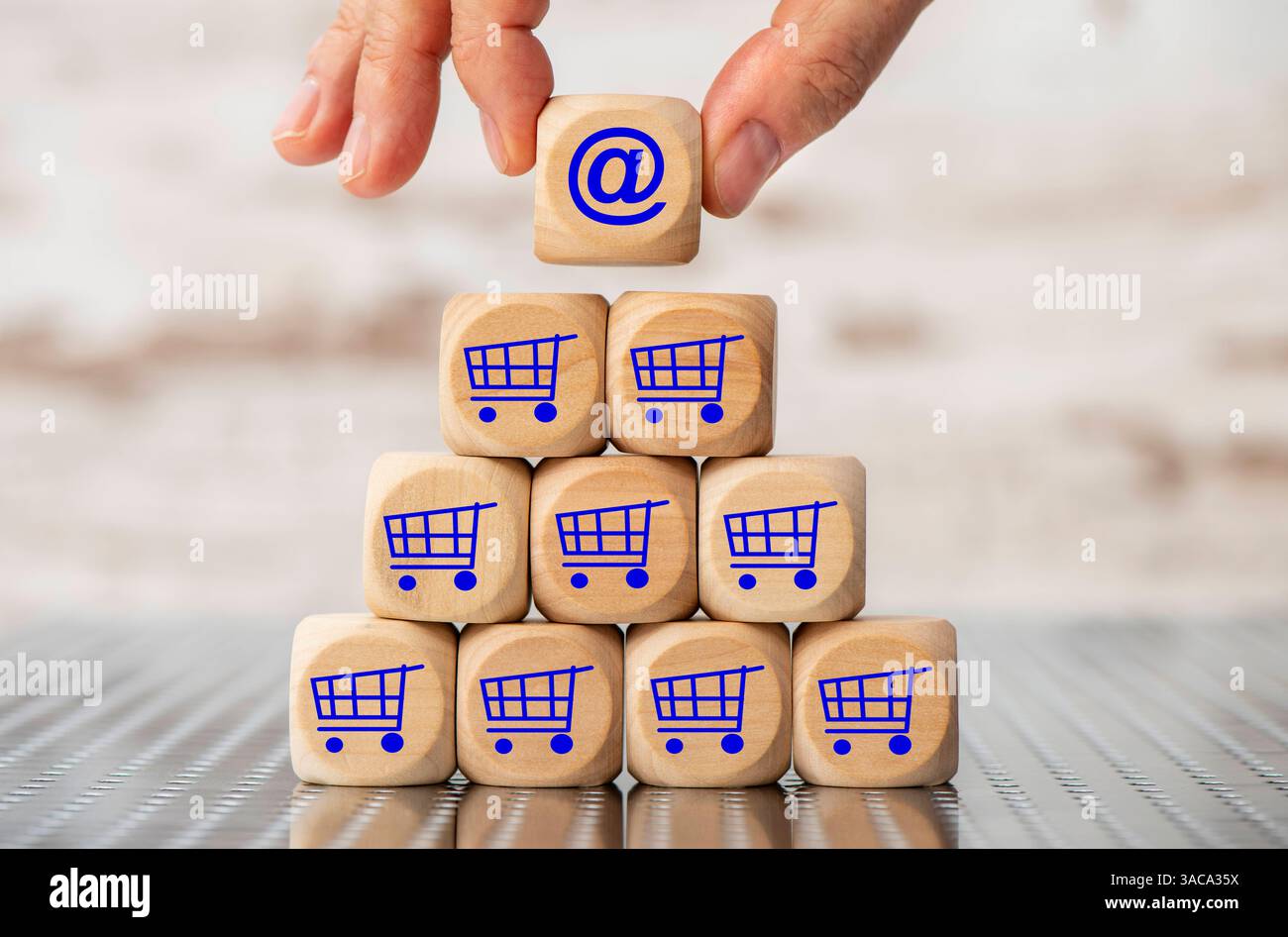 Online Shopping im Internet eine Holzpyramide aus Würfel ist bedruckt mit dem Symbol eines Einkaufswagens und eine Hand hält einen Holzwürfel in der Ha Stockfoto
