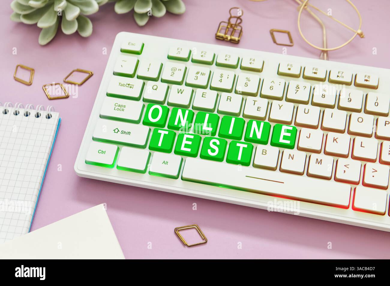 Online-Test. Computertastatur mit Wörtern und Schreibwaren auf rosa Tisch Stockfoto