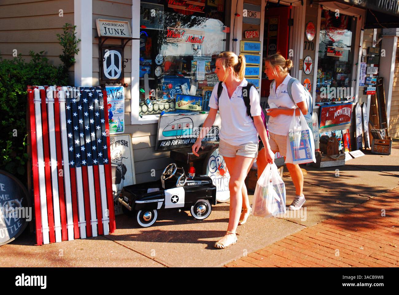 Zwei Freundinnen spazieren durch die Innenstadt von Montauk, New York, auf Long Island, und schauen sich einen Antiquitätenladen an, in dem Vintage-Spielzeug verkauft wird Stockfoto