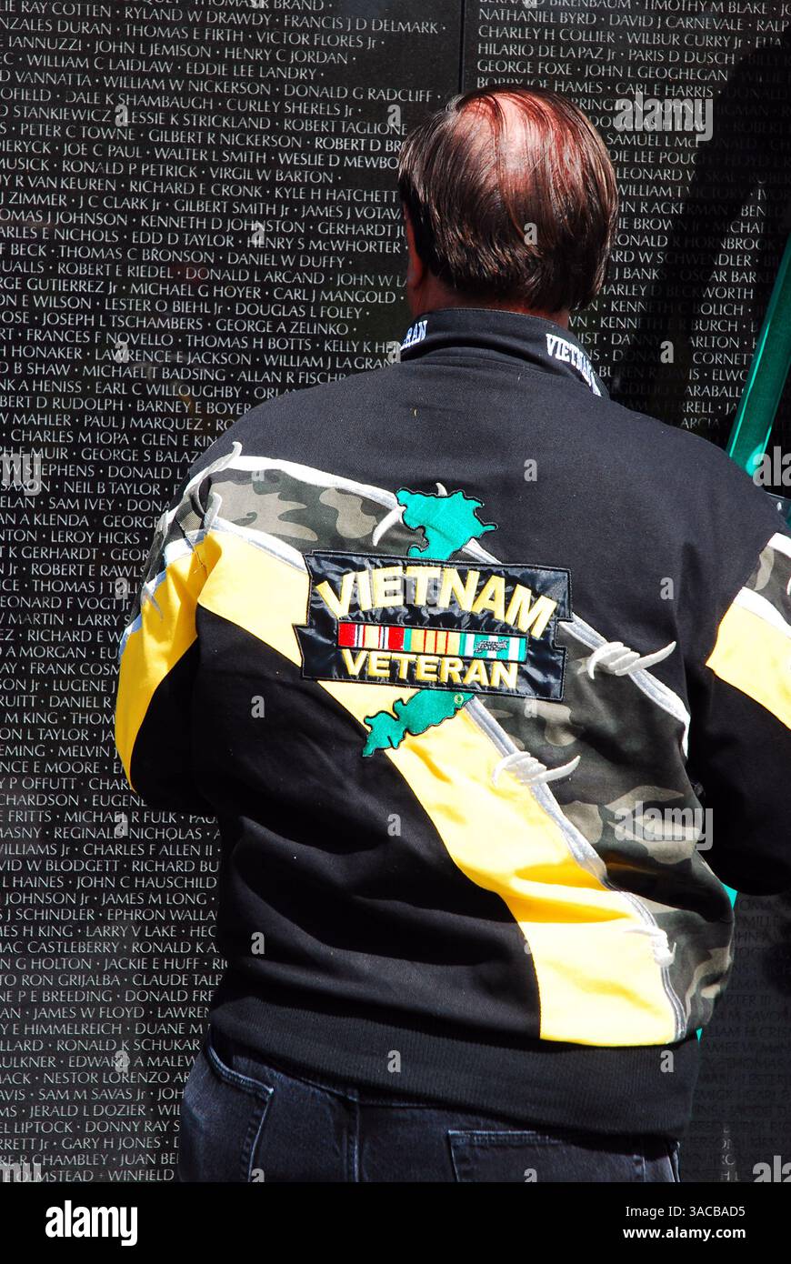 In einem düsteren Moment hält ein Mann in einer Vietnam Veteranenjacke inne, um die Namen auf dem Vietnam Veterans Memorial in W zu lesen Stockfoto