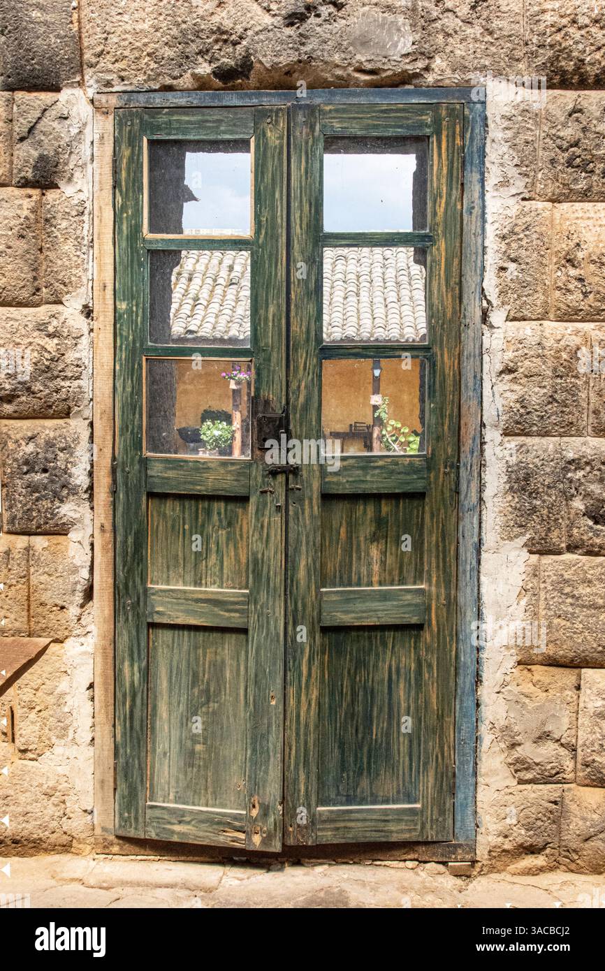 Alte Holztür mit abgenutzter grüner Farbe schmiegt sich zwischen die Wände, die von den Inka in den 1440er Jahren in Ecuador gebaut wurden. (Nur Für Redaktionelle Zwecke) Stockfoto