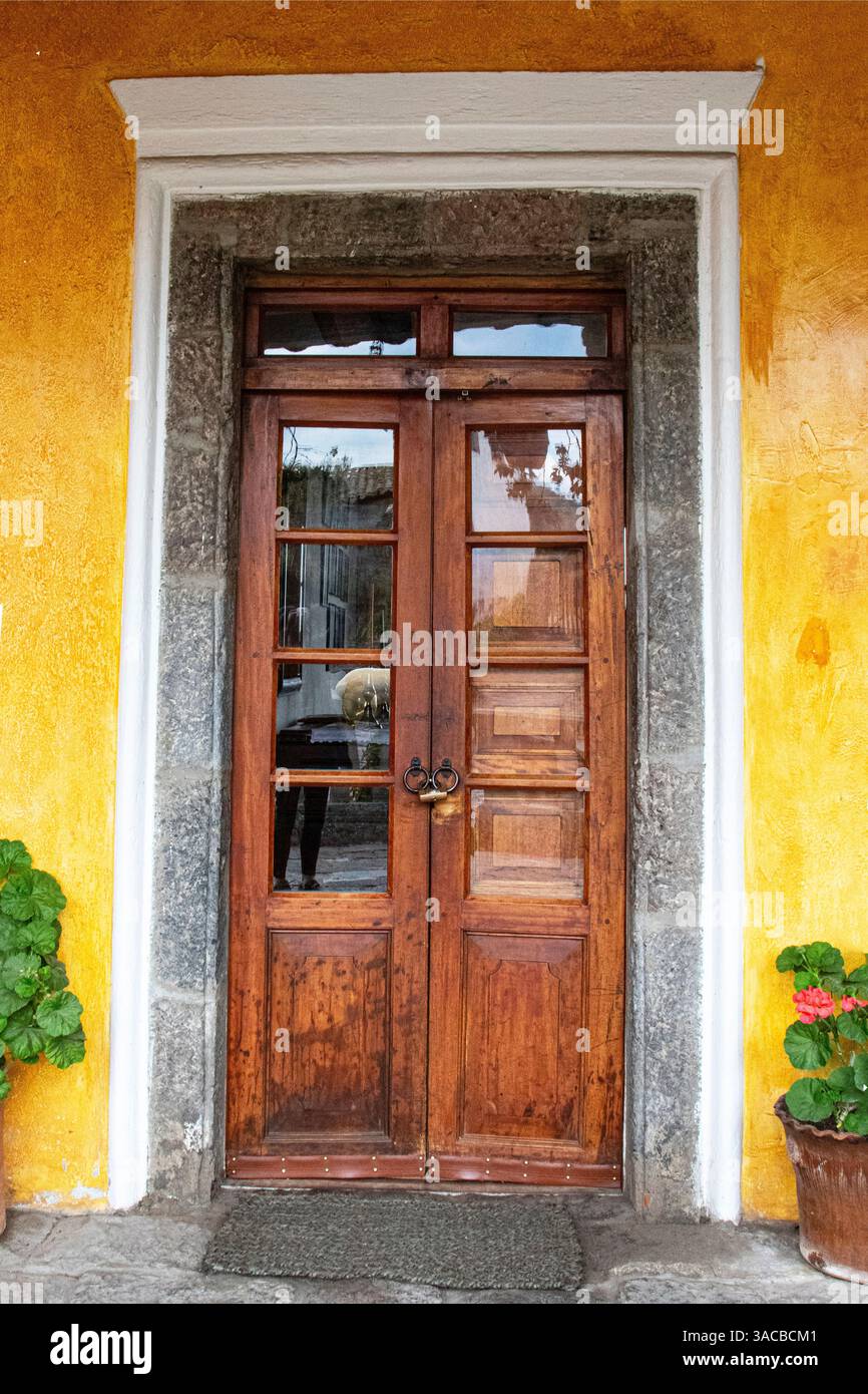 Alte hölzerne Tür flankiert von zwei Geranienpflanzen in der Hacienda San Augustin de Callo in der Region Cotopaxi in Ecuador. (Nur Für Redaktionelle Zwecke) Stockfoto