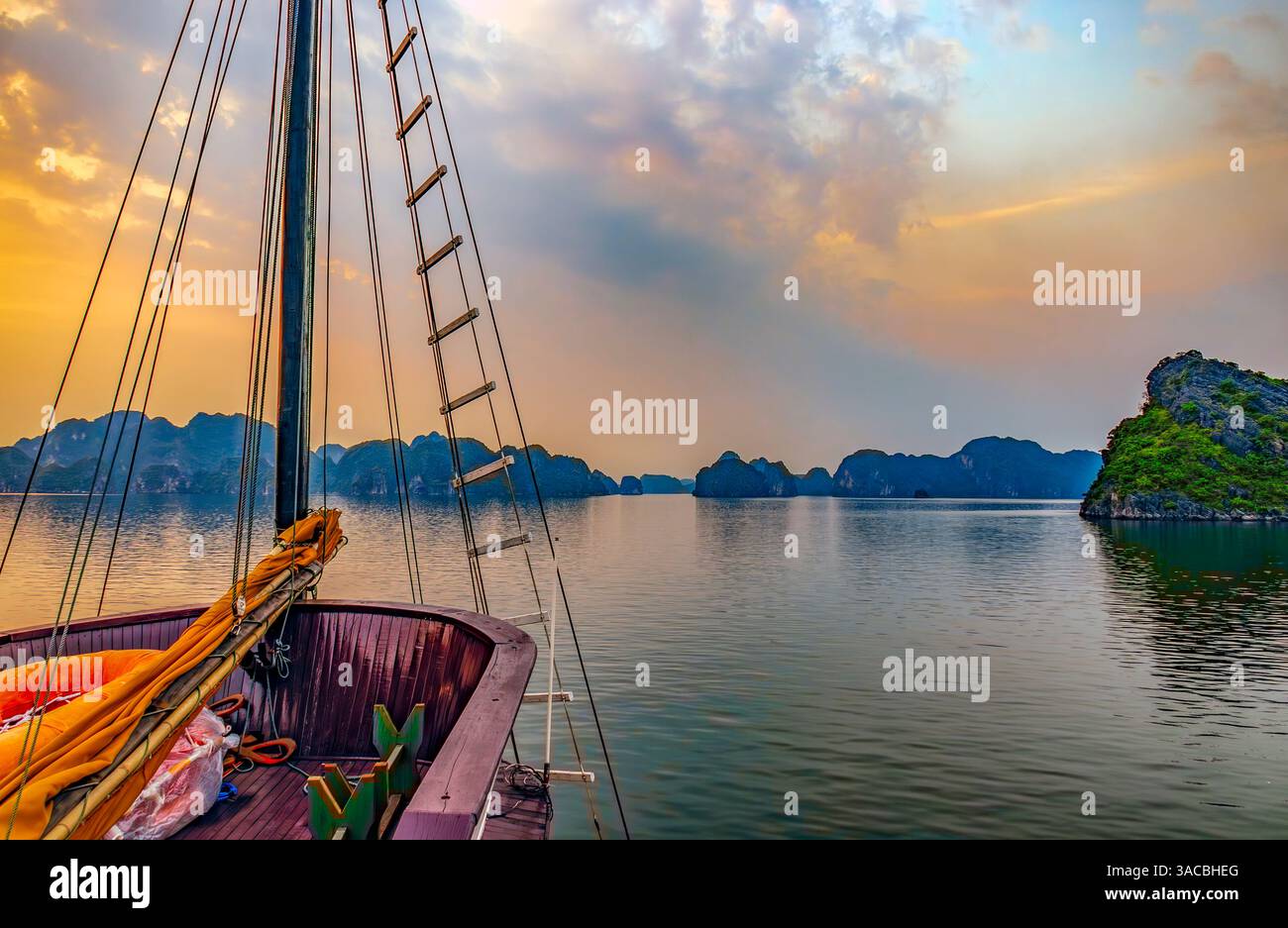 Ha Long Bay, Vietnam. Weitwinkelblick auf das Touristenboot bei Sonnenuntergang zwischen den Kalksteinkarsten und Inselchen. Stockfoto