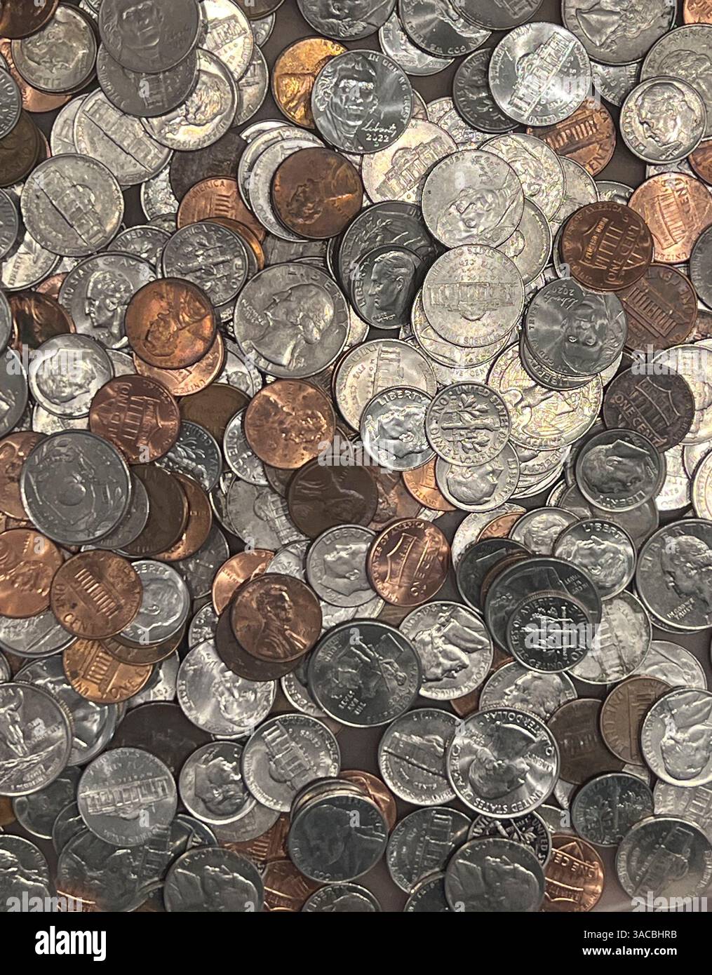 Verschiedene amerikanische Münzen unterschiedlicher Stückelungen sind auf einer flachen Oberfläche verteilt und zeigen eine Mischung aus Kupfer, Nickel und Silber. Einige Co und Stockfoto