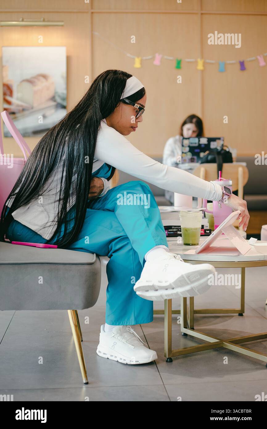 Eine Frau in Krankenschwesteruniform benutzt eine Tablette im Elkins Park, Pennsylvania, USA, 3. April 2025 Stockfoto