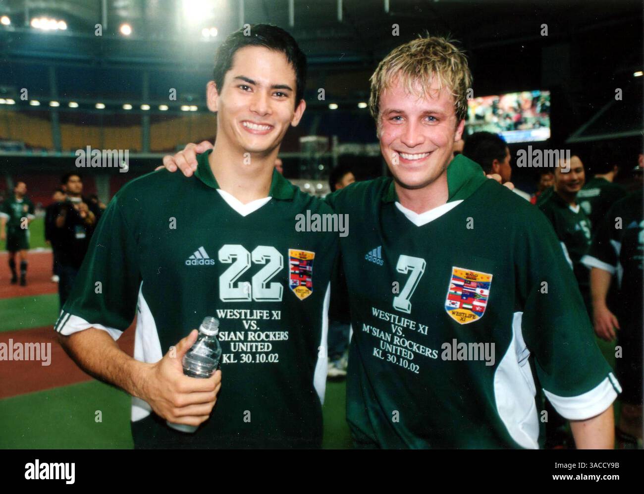30. Oktober 2002.Malaysia, Kuala Lumpur. „Man of the Match“ Kian Egan von Westlife mit „Playmaker“ Alex Yoong (mal). Die irische Boyband WESTLIFE, bestehend aus Kian Egan, Nicky Byrne, Bryan McFadden, Shane Filan und Mark Feehily, war für einen 3-tägigen Besuch in Malaysia, um ihr neuestes Album, eine Compilation mit dem Titel Unbreakable, zu promoten. Dies ist das erste Land in Asien, das von der Band besucht wird. Die Fans wurden durch ein kurzes Konzert unterhalten und spielten Fußball für eine lokale Wohltätigkeitsorganisation. Das spannende Fußballspiel bestand auch aus Formel-1-Fahrer Alex Yoong (mal) und anderen lokalen Stars Stockfoto