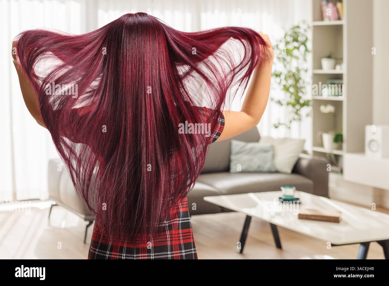 Rückansicht einer Frau mit langen Haaren, die in einem Wohnzimmer steht Stockfoto