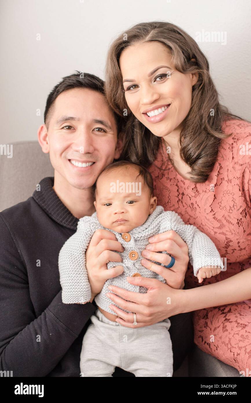 Glückliche Eltern kuscheln ihr Baby für ein süßes Familienporträt zu Hause Stockfoto