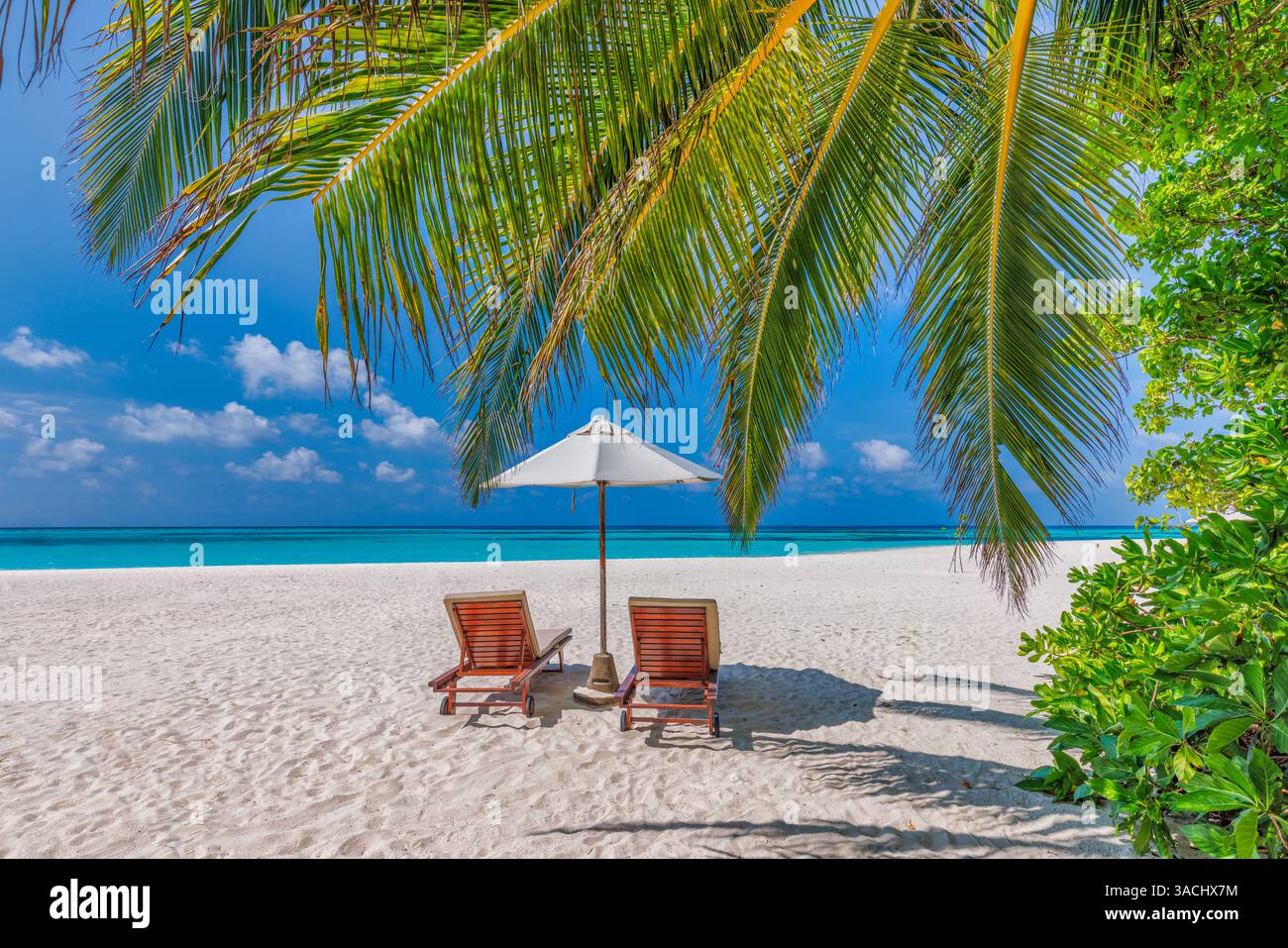 Romantischer, sonniger tropischer Strand, Liegen, Sonnenschirme, Palmen auf Sand, ruhiger Meerblick, glückliches Paradies Entspannung am Ufer. Fantastisches Urlaubskarton Stockfoto