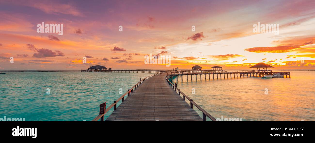 Fantastisches Panorama bei Sonnenuntergang auf den Malediven. Luxuriöse Resort Villen Pier Path Seascape sanfte LED Lichter unter buntem Himmel. Wunderschöner Abendhimmel fantastische Wolken. Stockfoto