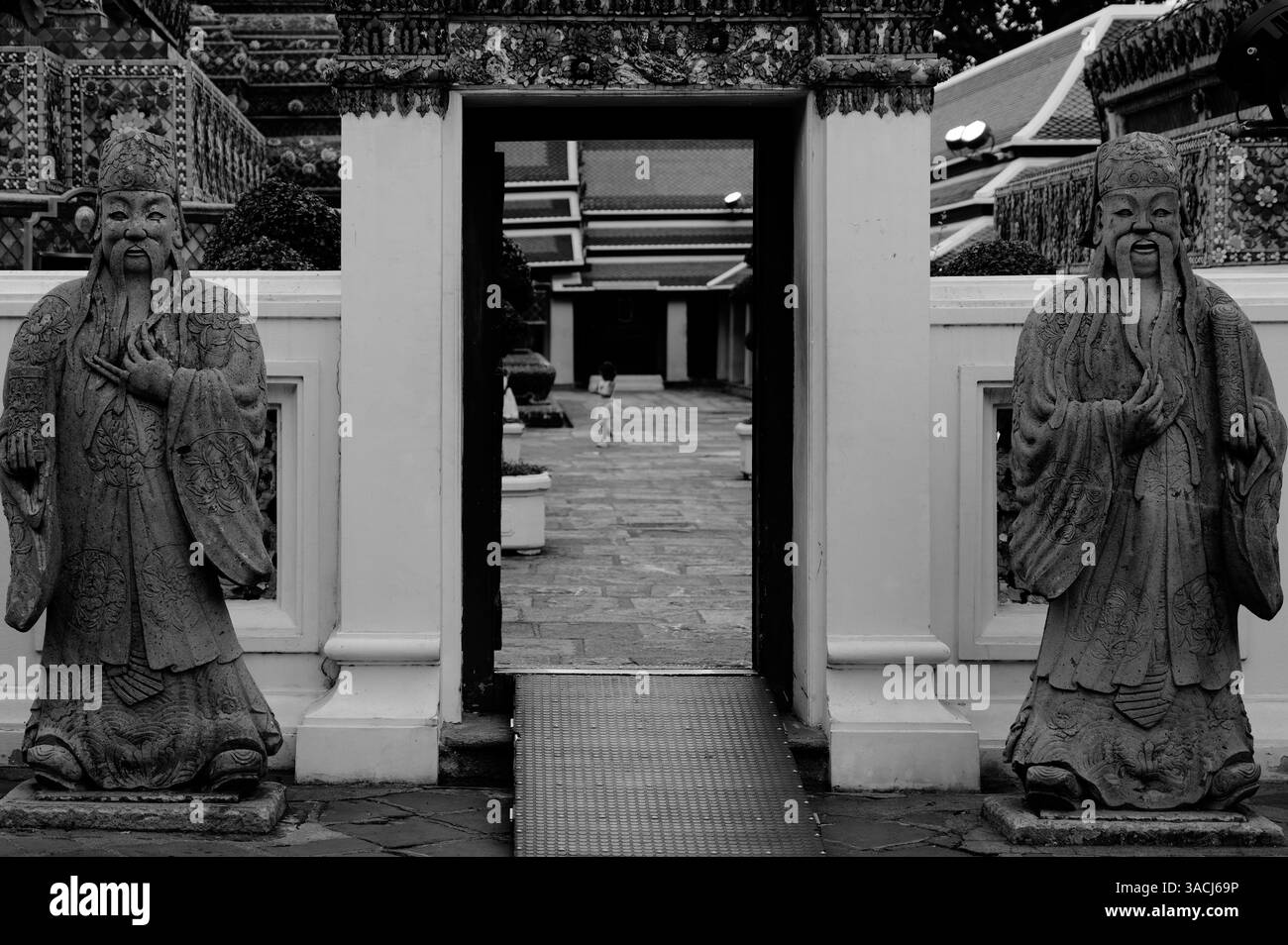 Zwischen den stillen Wächtern wandert ein Kind durch das Tempelgelände des Wat Pho Stockfoto