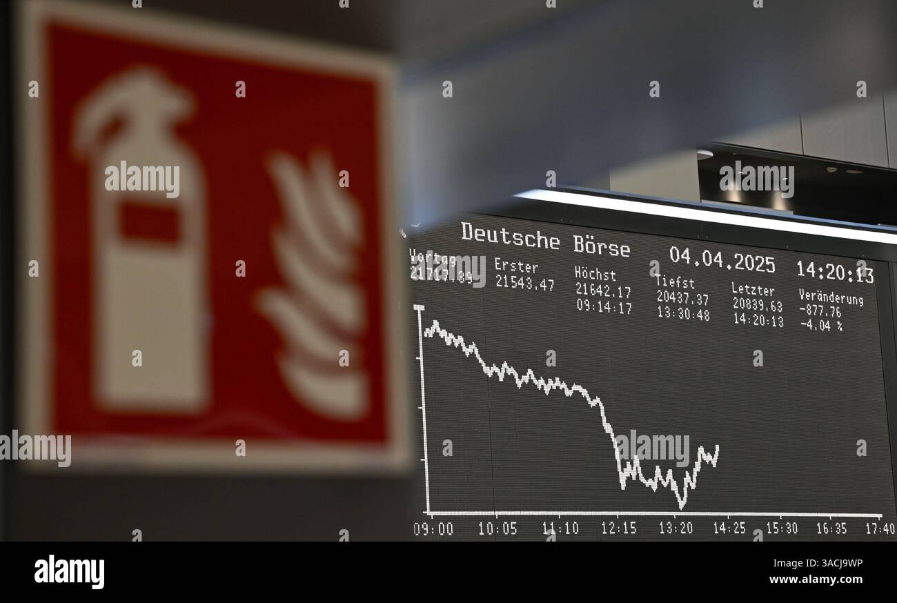 04. April 2025, Hessen, Frankfurt/Main: An einer Passage der Frankfurter Wertpapierbörse ist ein Feuerlöschschild zu sehen, während die Anzeigetafel mit der Dax-Kurve fallende Preise anzeigt. US-Präsident Trump hatte ein riesiges Zollpaket gegen Handelspartner auf der ganzen Welt veröffentlicht. Die Europäische Union und China haben bereits Gegenmaßnahmen angekündigt. Foto: Arne Dedert/dpa Stockfoto
