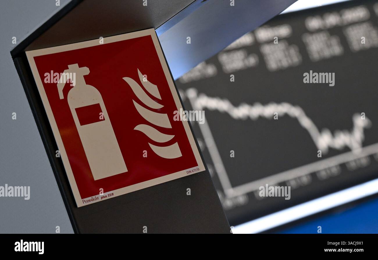 04. April 2025, Hessen, Frankfurt/Main: An einer Passage der Frankfurter Wertpapierbörse ist ein Feuerlöschschild zu sehen, während die Anzeigetafel mit der Dax-Kurve fallende Preise anzeigt. US-Präsident Trump hatte ein riesiges Zollpaket gegen Handelspartner auf der ganzen Welt veröffentlicht. Die Europäische Union und China haben bereits Gegenmaßnahmen angekündigt. Foto: Arne Dedert/dpa Stockfoto