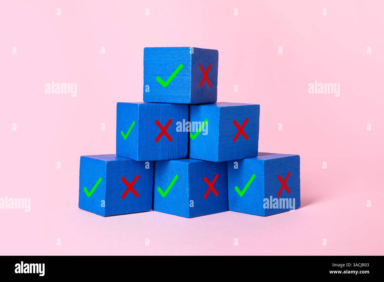 Ablehnung genehmigen. Pyramide aus Holzwürfeln mit Karo- und Kreuzmarkierungen auf rosafarbenem Hintergrund Stockfoto