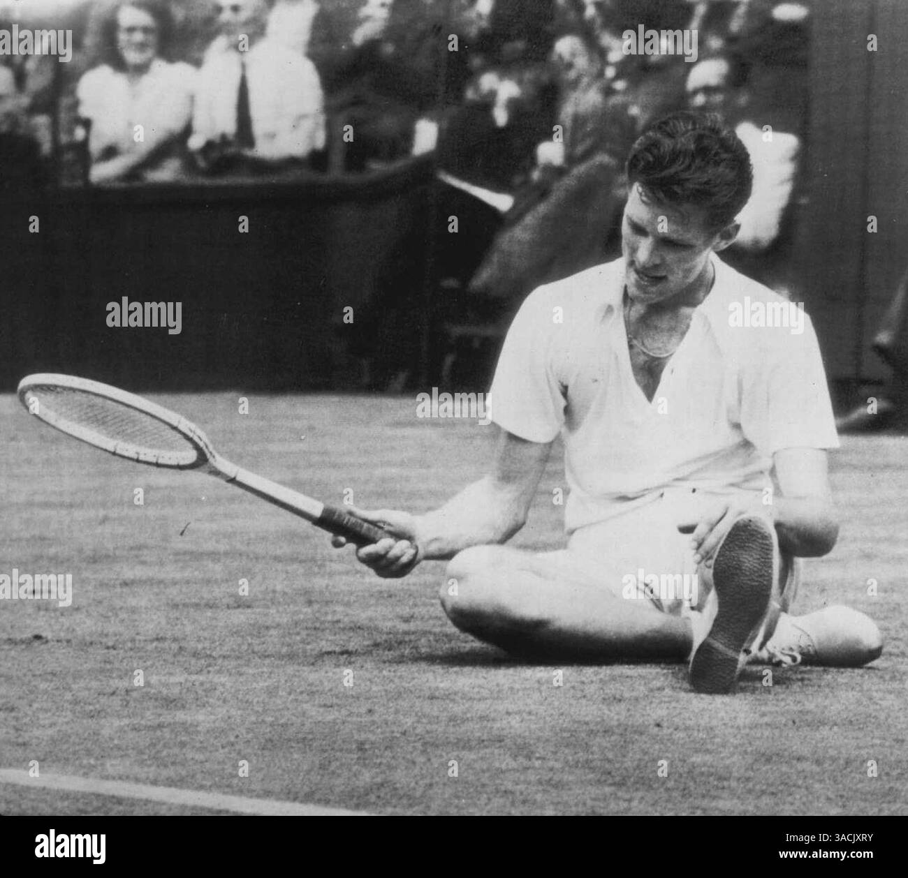 Budge Patty, unbesetzter US-Tennisspieler, hockt am 28. Juni in Wimbledon, England, auf dem Rasen, um nach einer Siegerrallye in seinem Match mit John Bronwich, australischem Champion, bei den Männer-Einzelmeisterschaften zu atmen. Patty erzielte eine atemberaubende Verärgerung, indem er Bromwich 6-4, 0-6, 6-4, 1-6, 6:4, in der vierten Runde der Singles. 30. Juni 1947. (Foto von AP Wirephoto) Stockfoto