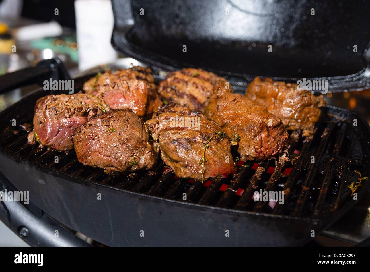 Saftiges Rindfleischfilet Mignon Steaks, gegrillt auf einem elektrischen Grill mit sichtbaren Kräutern und Brandspuren, perfekt gekocht. Stockfoto